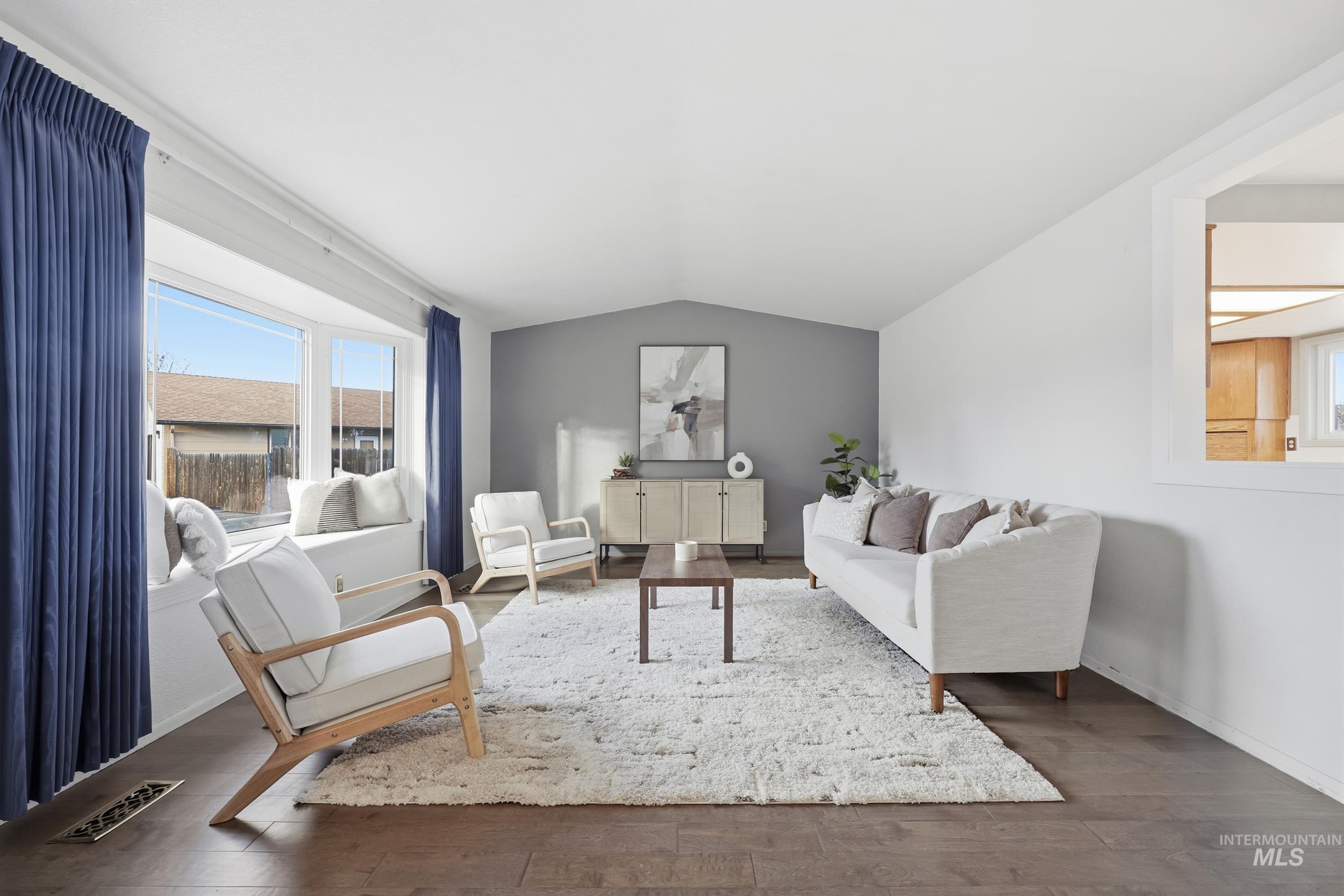 Living area with vaulted ceiling, new engineered hardwood floors and open view into the dining and kitchen area.