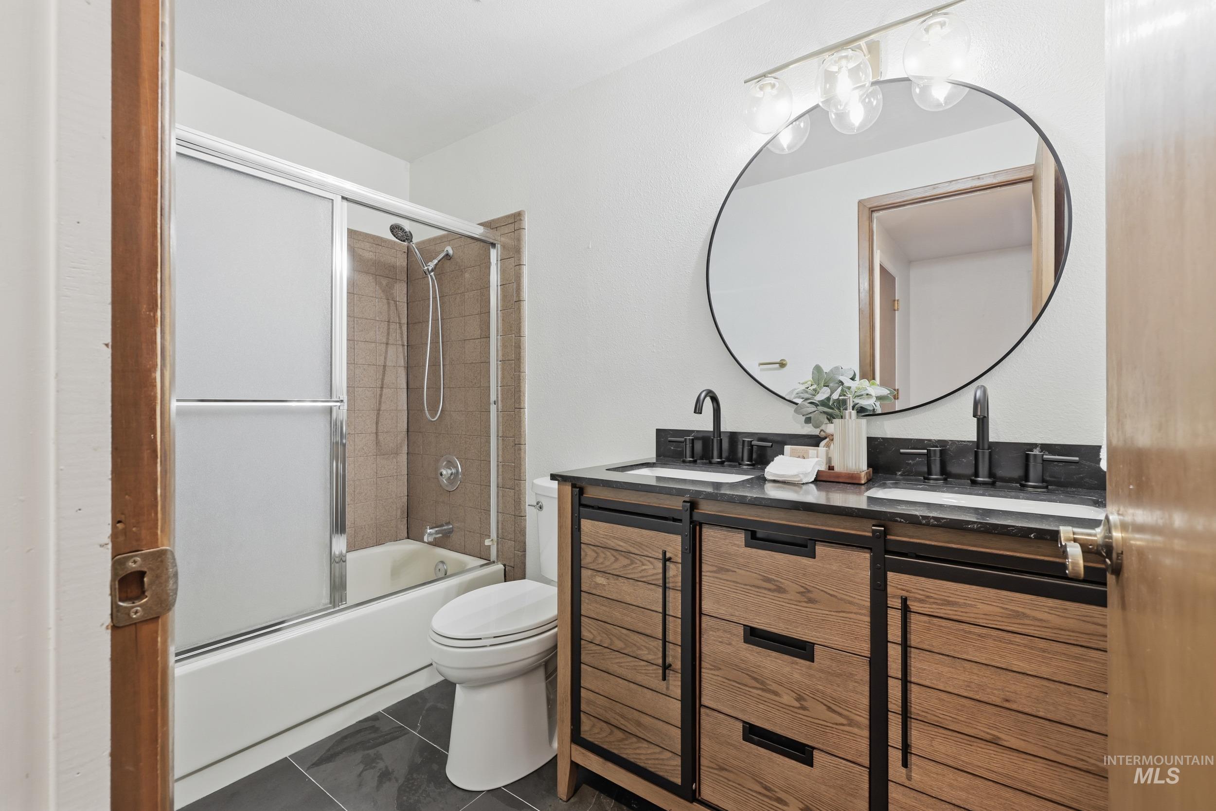 Full bathroom with shower/bath combination with an updated vanity and tile floors.