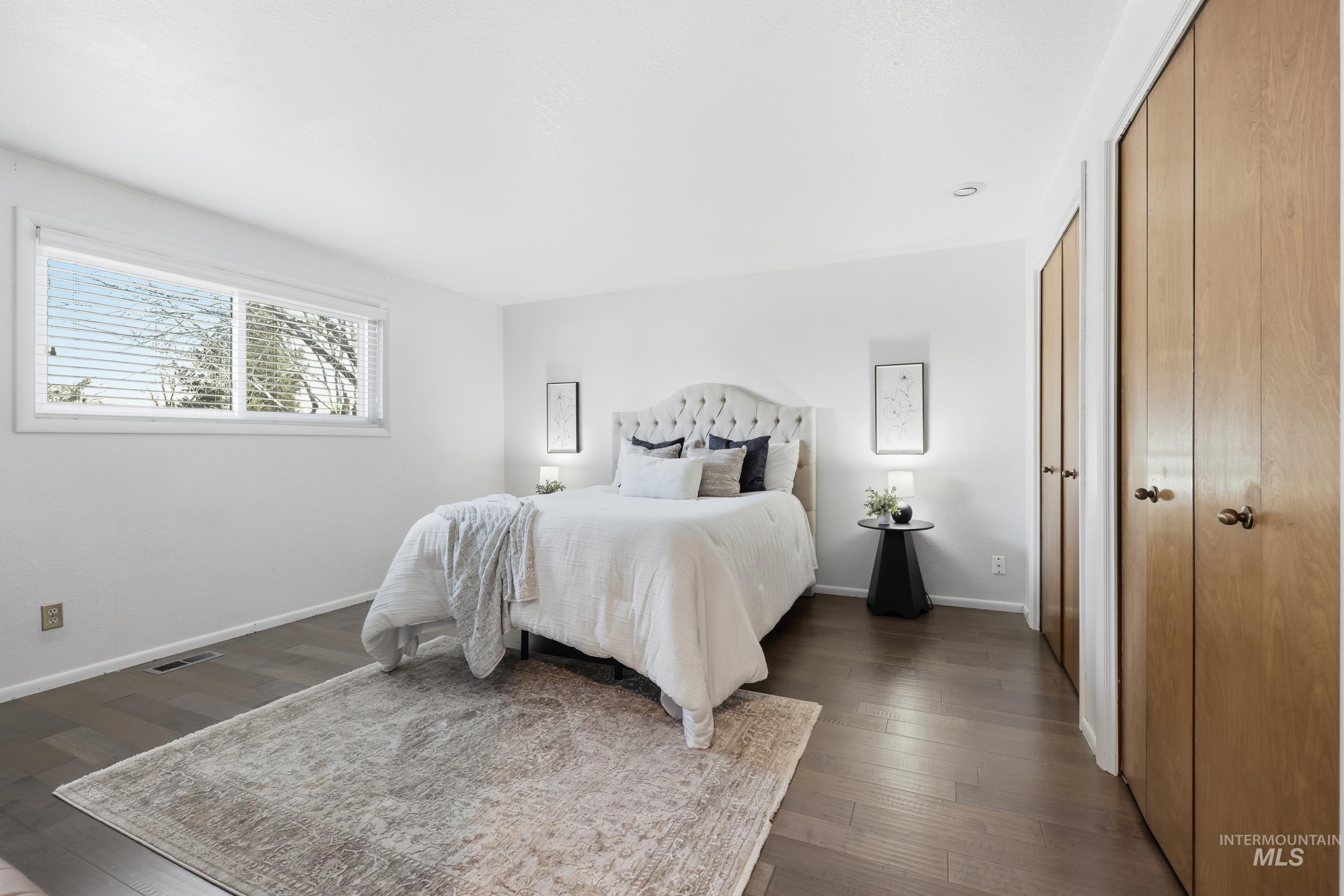 Bedroom featuring new engineered hardwood flooring, and multiple closet spaces.