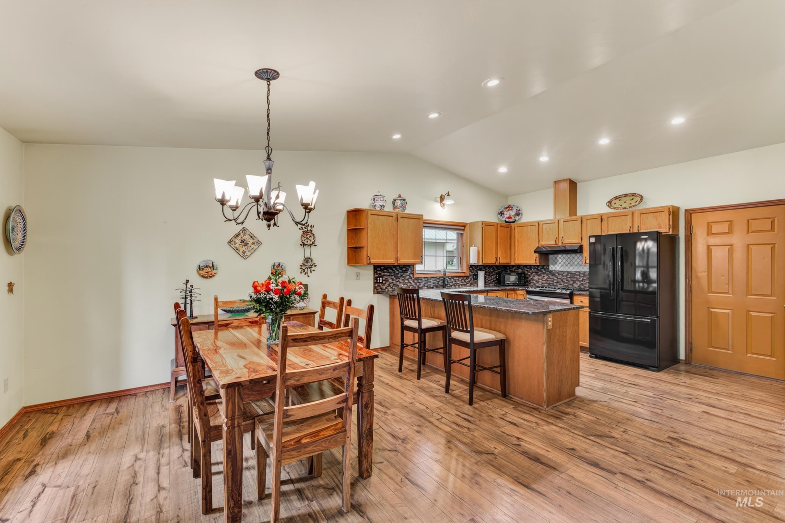 Open-concept living space featuring wood-finish flooring, vaulted ceilings, and recessed lighting