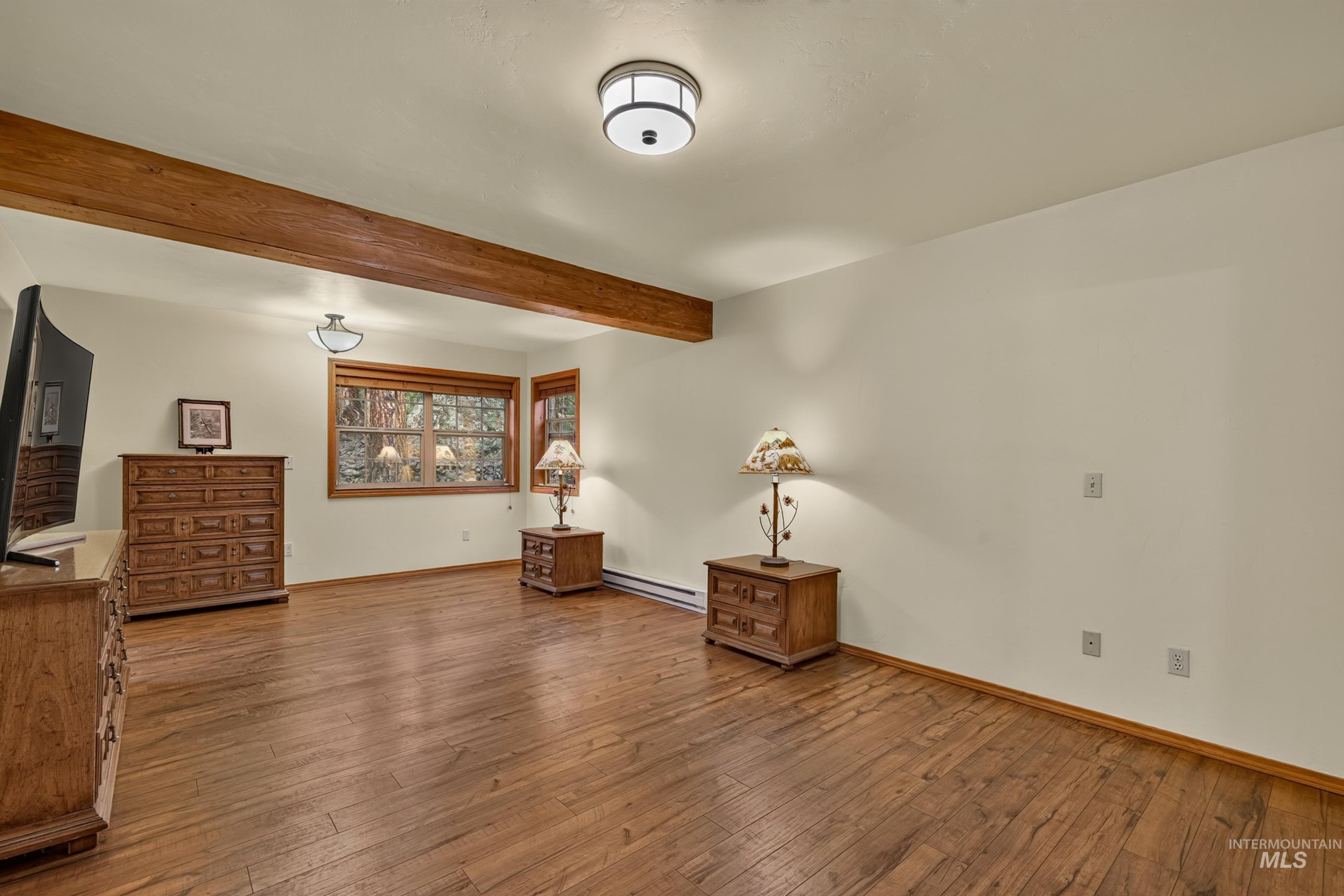 Spacious interior featuring wood-finish flooring, exposed ceiling beam, recessed lighting, and multiple windows