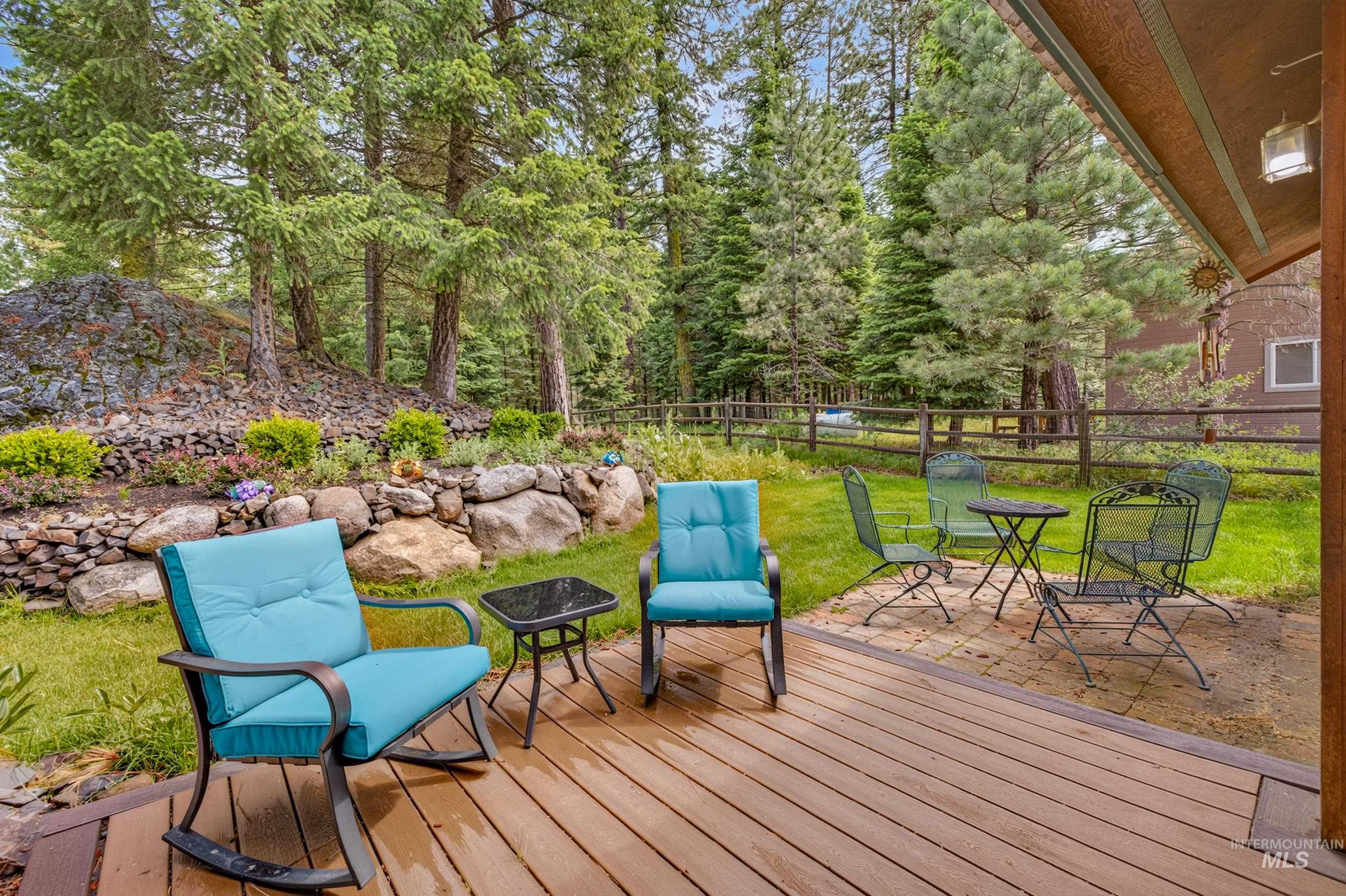 Expansive outdoor living area featuring a wood-finish deck, stone patio, and a terraced rock garden
