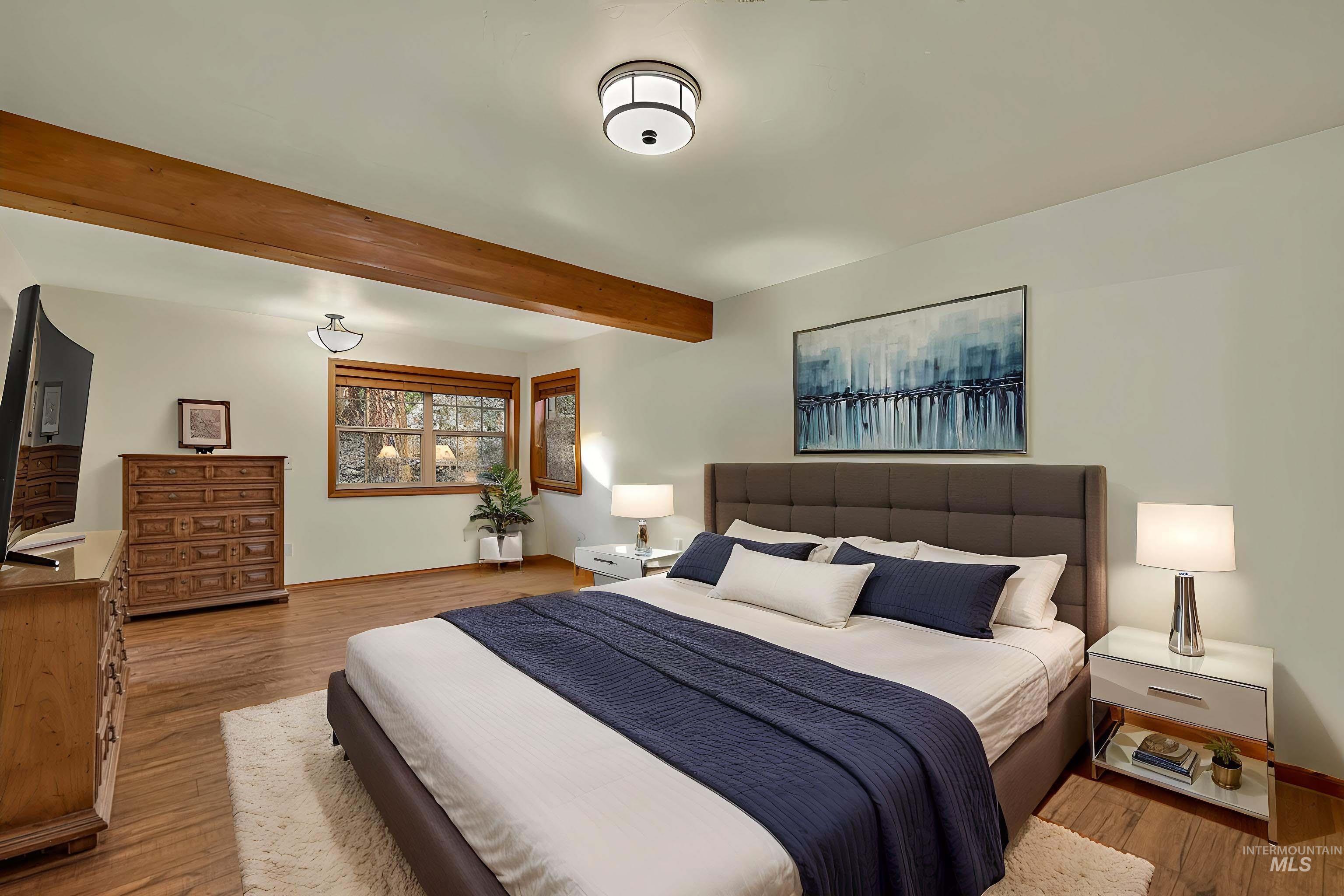 Spacious room with wood-finish flooring and exposed ceiling beams