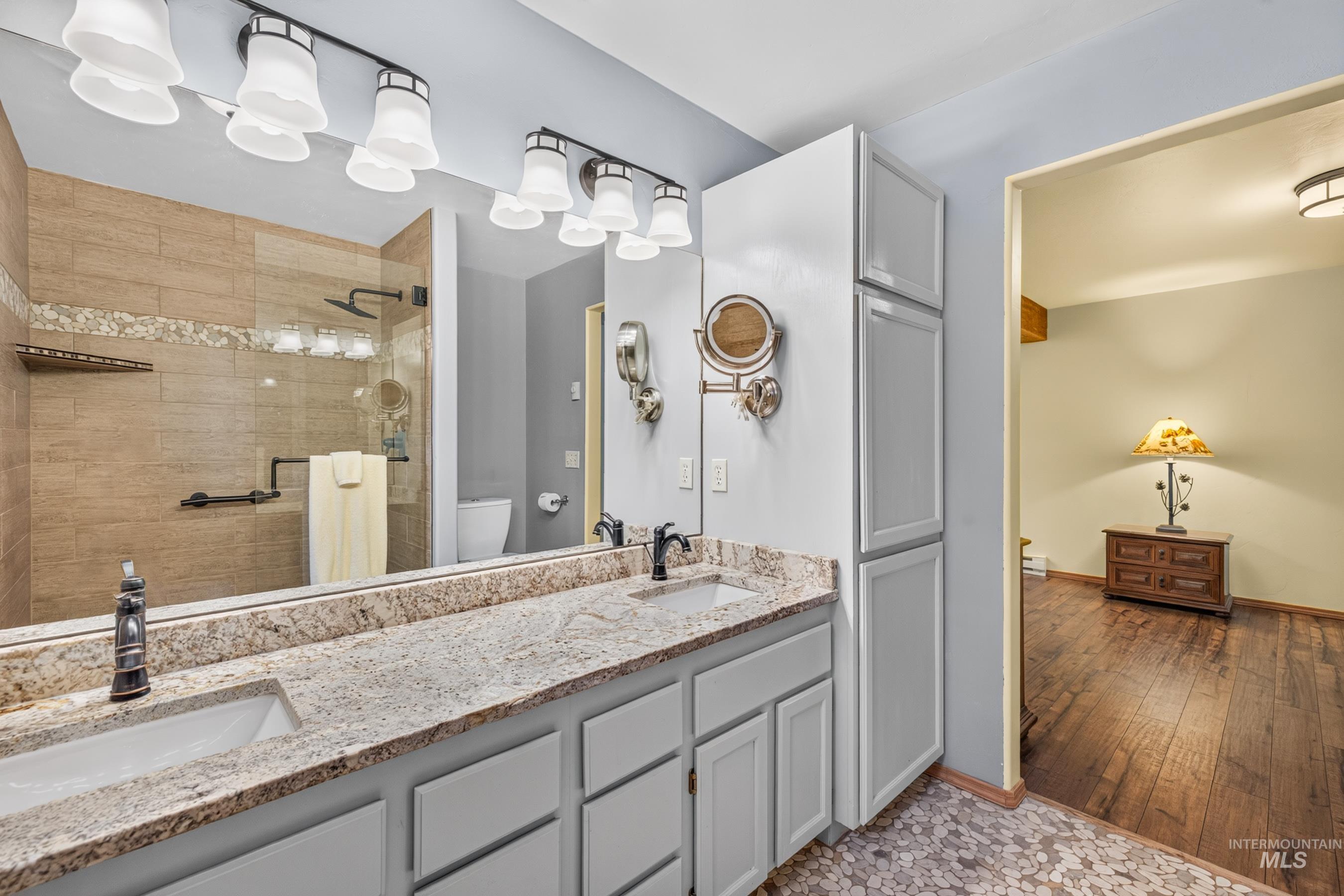 Bathroom featuring a double vanity with granite countertop, dual sinks, and white shaker-style cabinetry