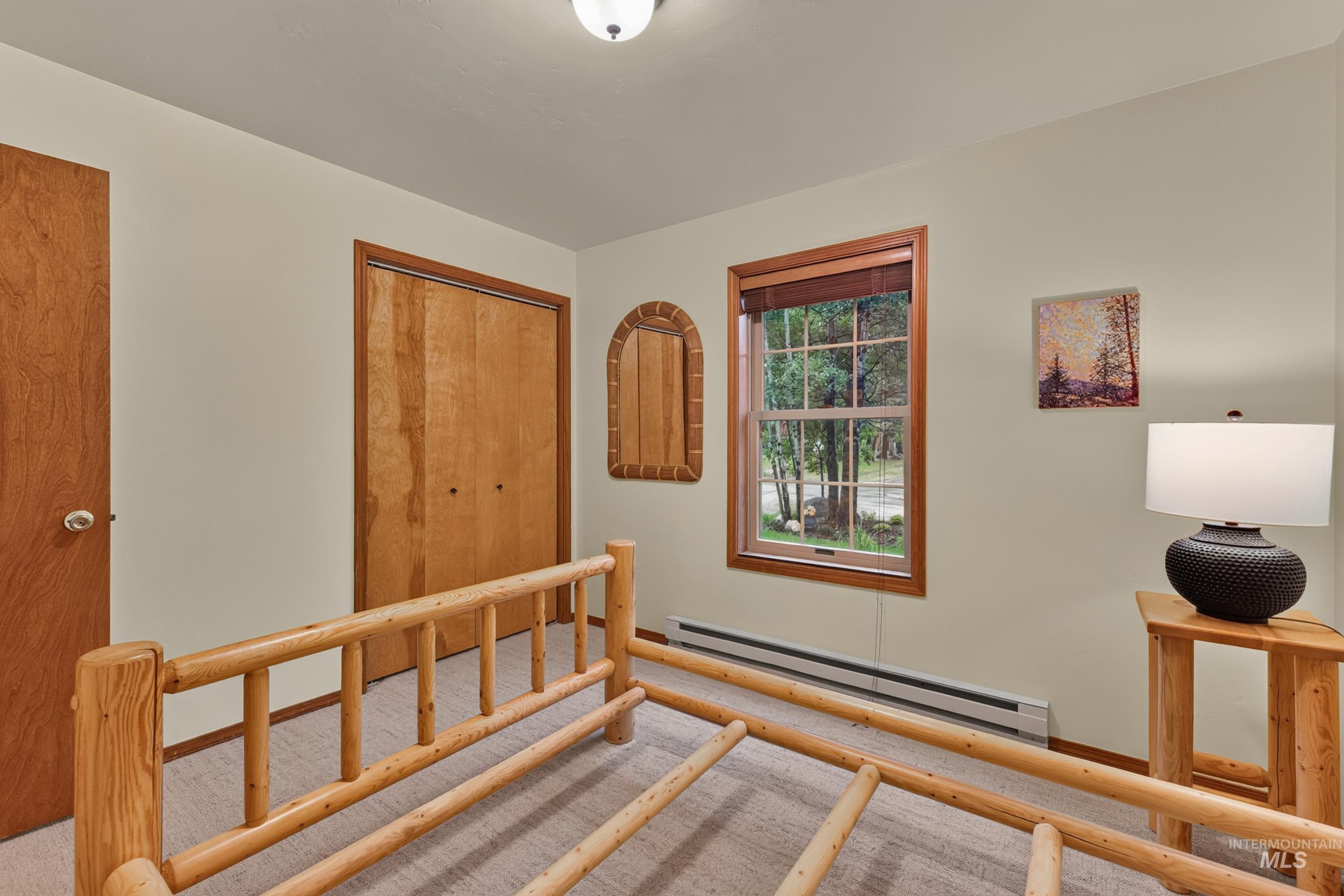 Bedroom featuring a double-pane window with wood-finish trim, light tan carpeting, and a built-in baseboard heater
