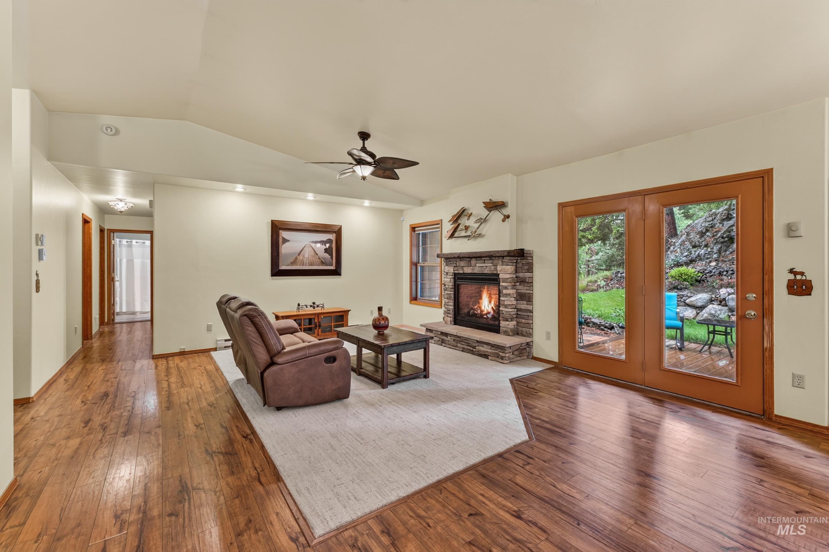 Spacious living area featuring wood-finish flooring, a stone-surround fireplace, and recessed lighting