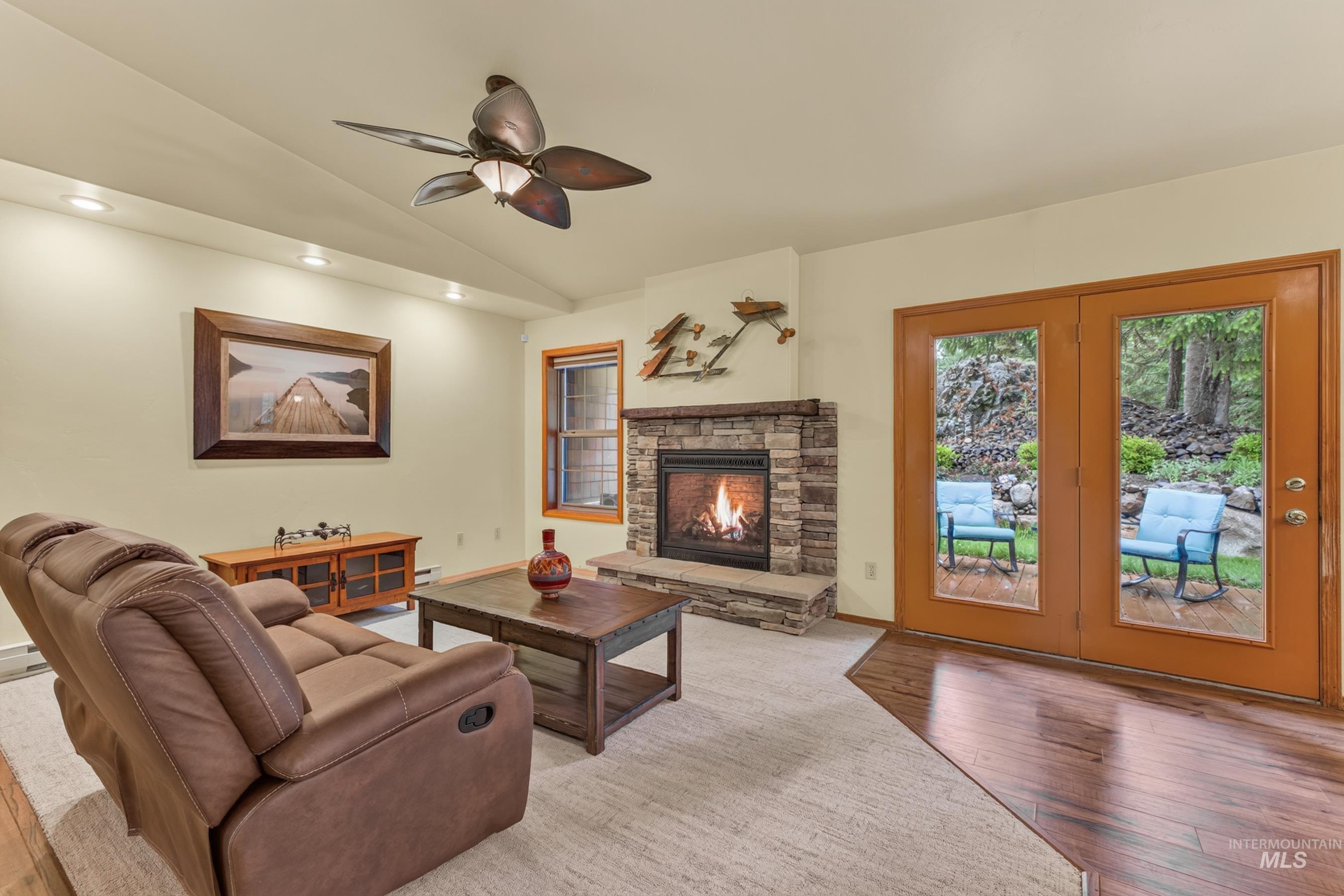 Living area featuring a stone-clad fireplace with hearth, wood-finish flooring, recessed lighting, and a ceiling fan