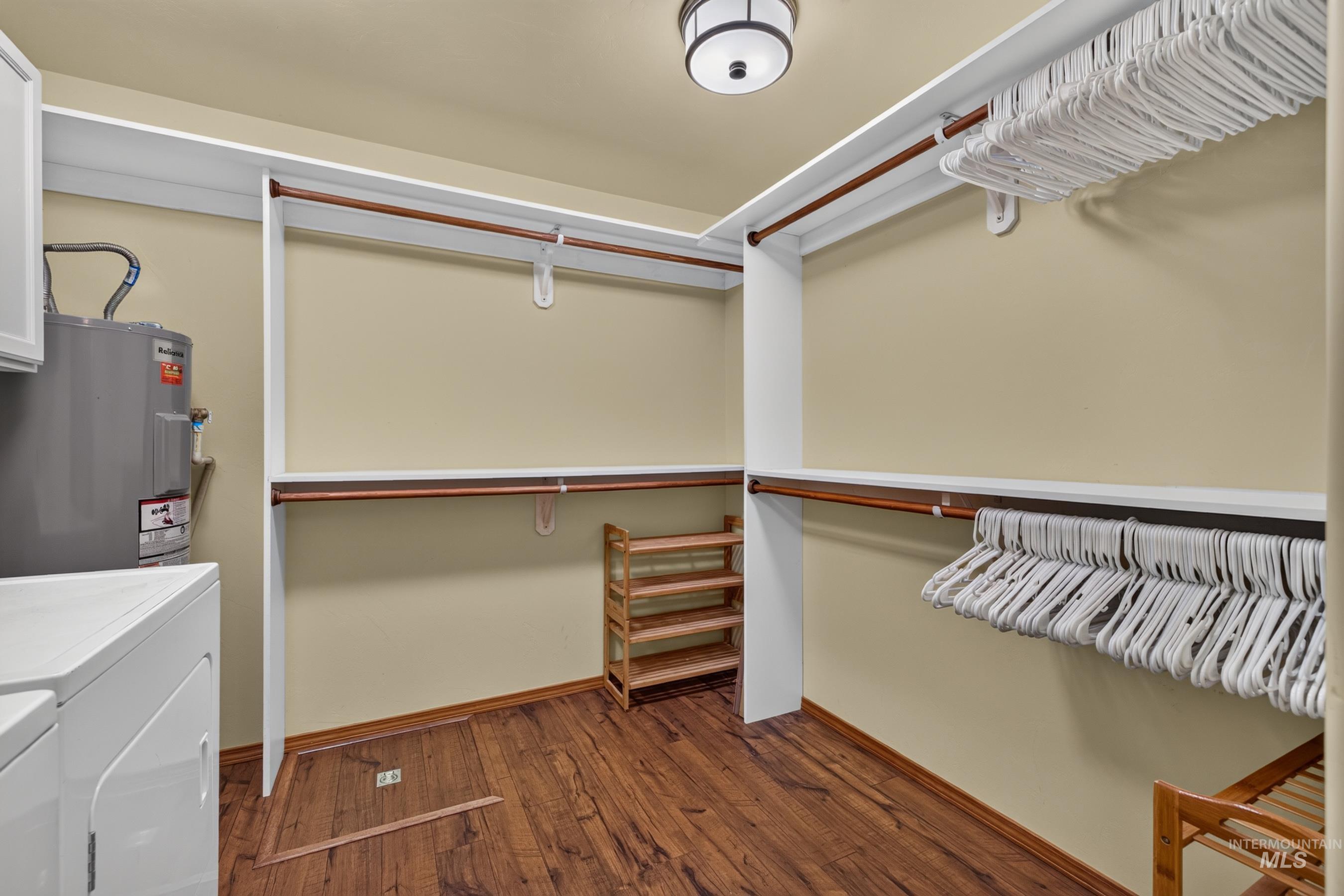 Laundry area with integrated closet system featuring wood-finish flooring, white shelving, and hanging rods