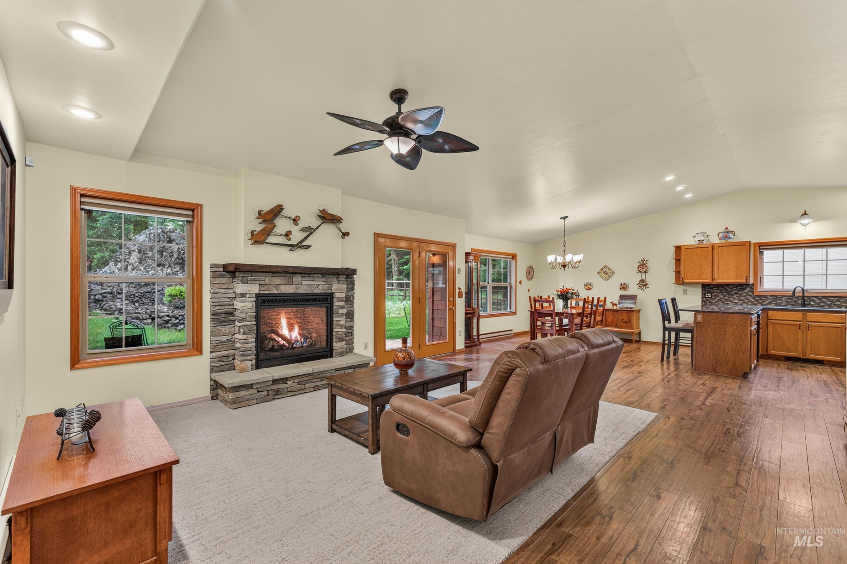 Living area featuring a stone-clad fireplace with a hearth, wood-finish flooring, and recessed lighting