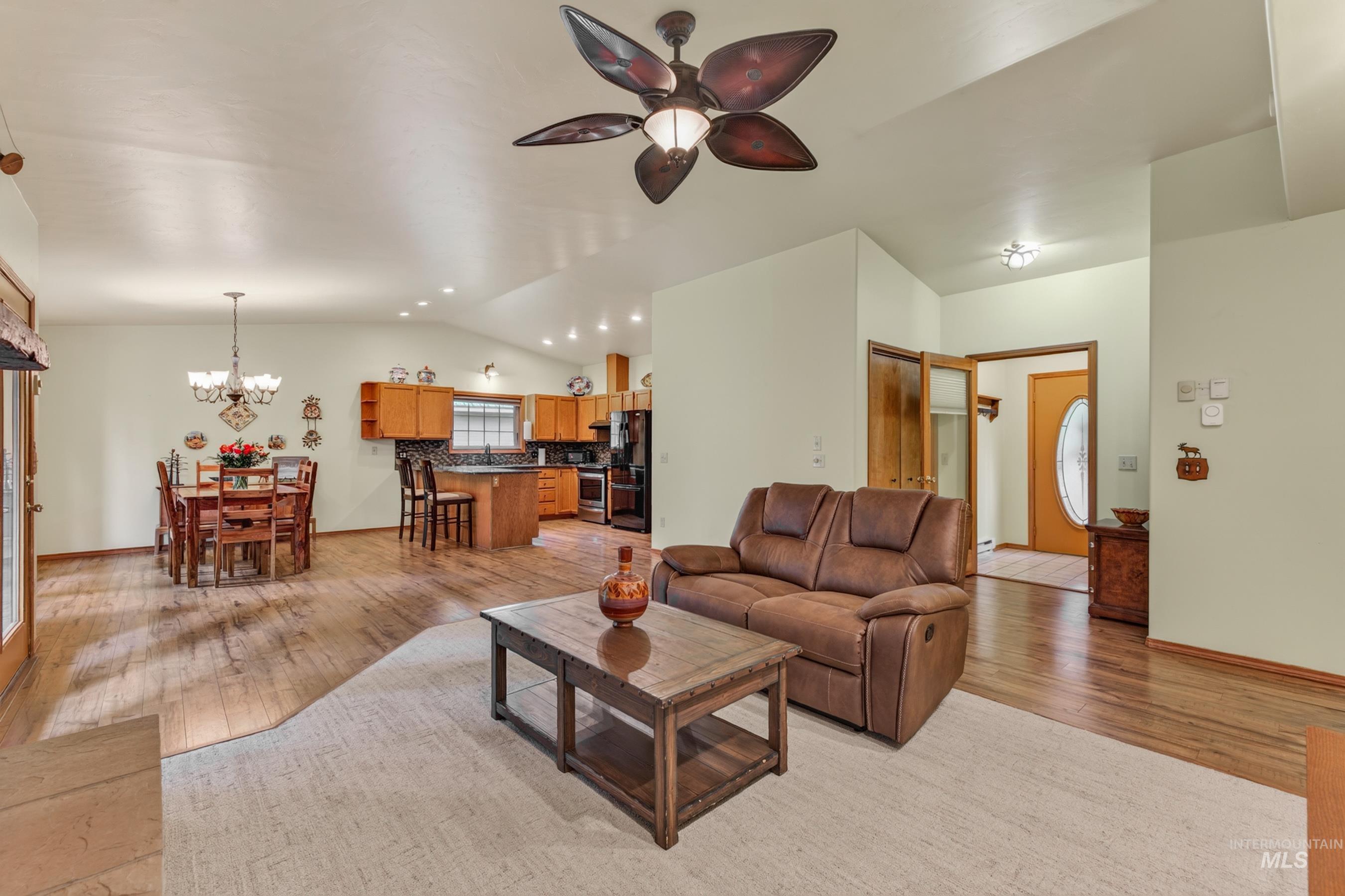 Open-concept living area featuring wood-finish flooring, a vaulted ceiling with a ceiling fan, and recessed lighting