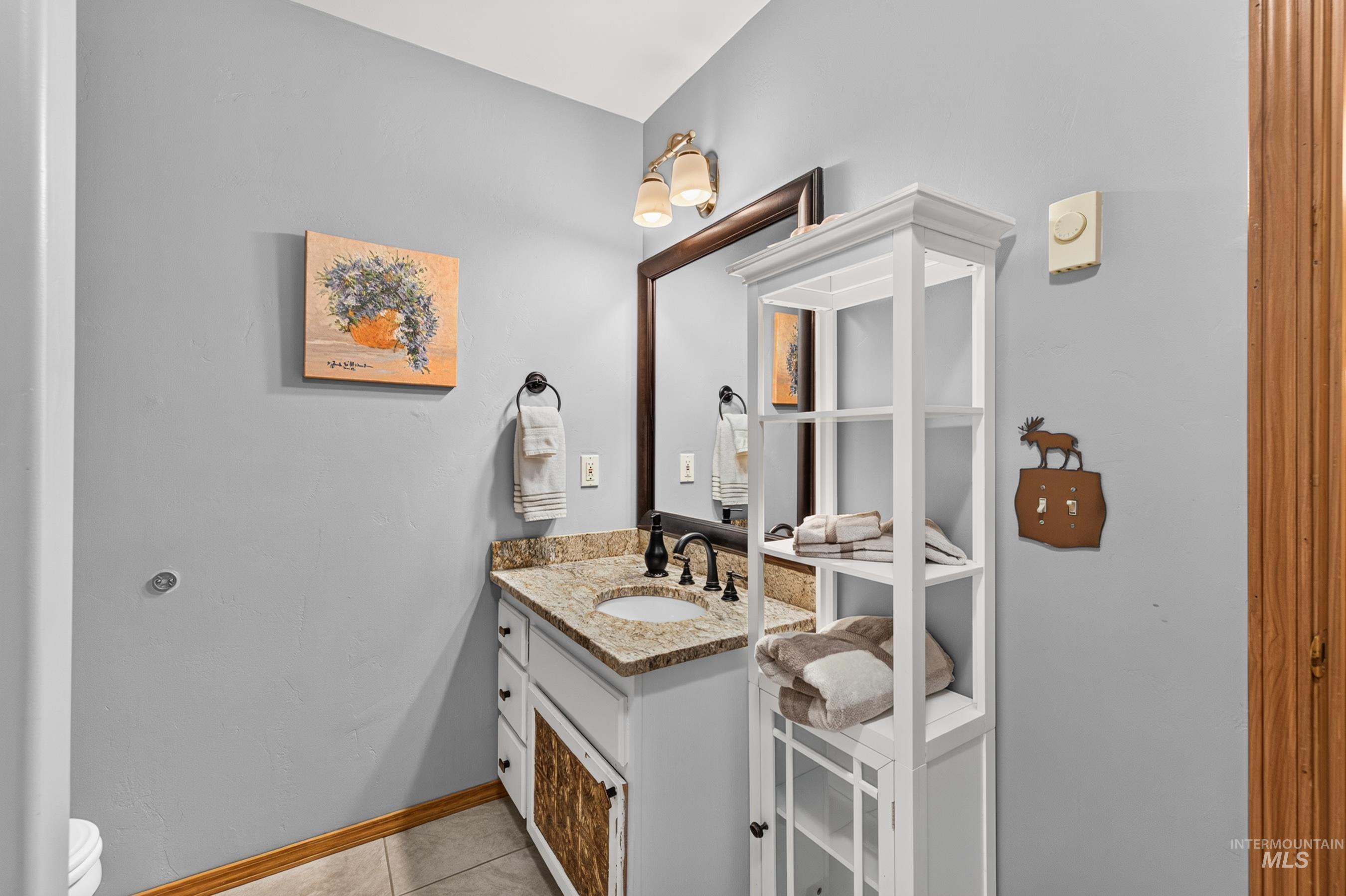 Bathroom vanity featuring a speckled countertop, undermount sink, and black faucet