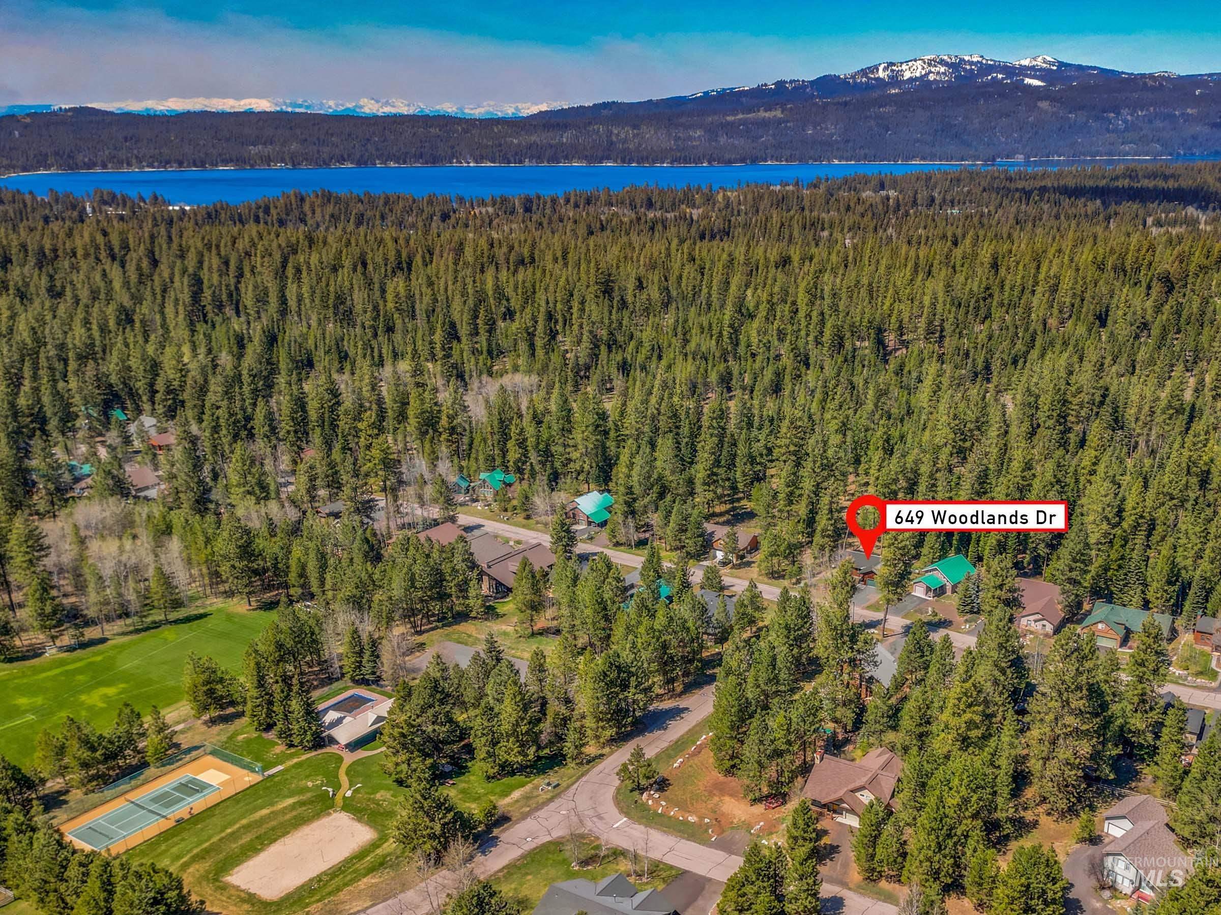 Aerial perspective showcasing a forested neighborhood with a prominent lake and distant mountains