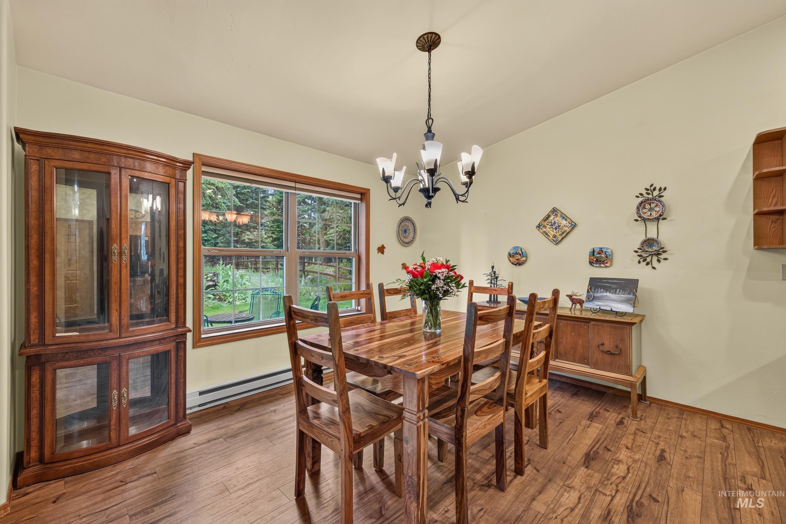 Dining area featuring wood-finish flooring, a multi-pane window with wood trim, and a ceiling-mounted chandelier