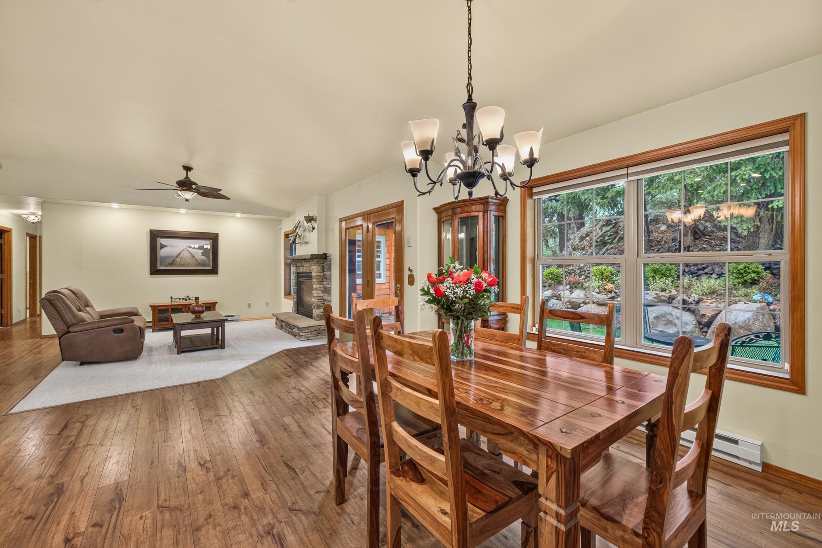 Dining area featuring wood-finish flooring, a wrought iron chandelier, and a large window with outdoor scenery