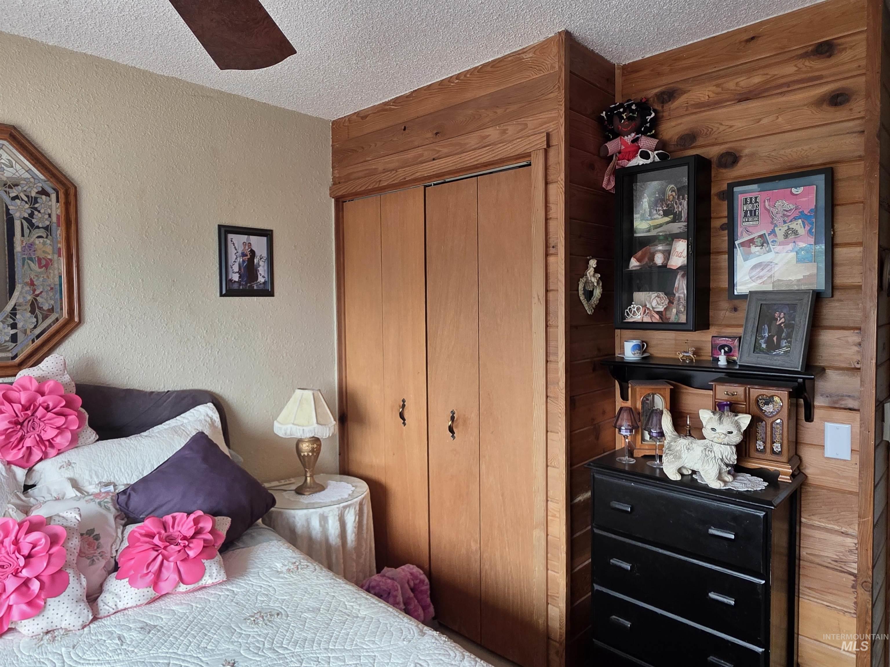Bedroom featuring a textured ceiling, a textured wall, a closet, and wooden walls