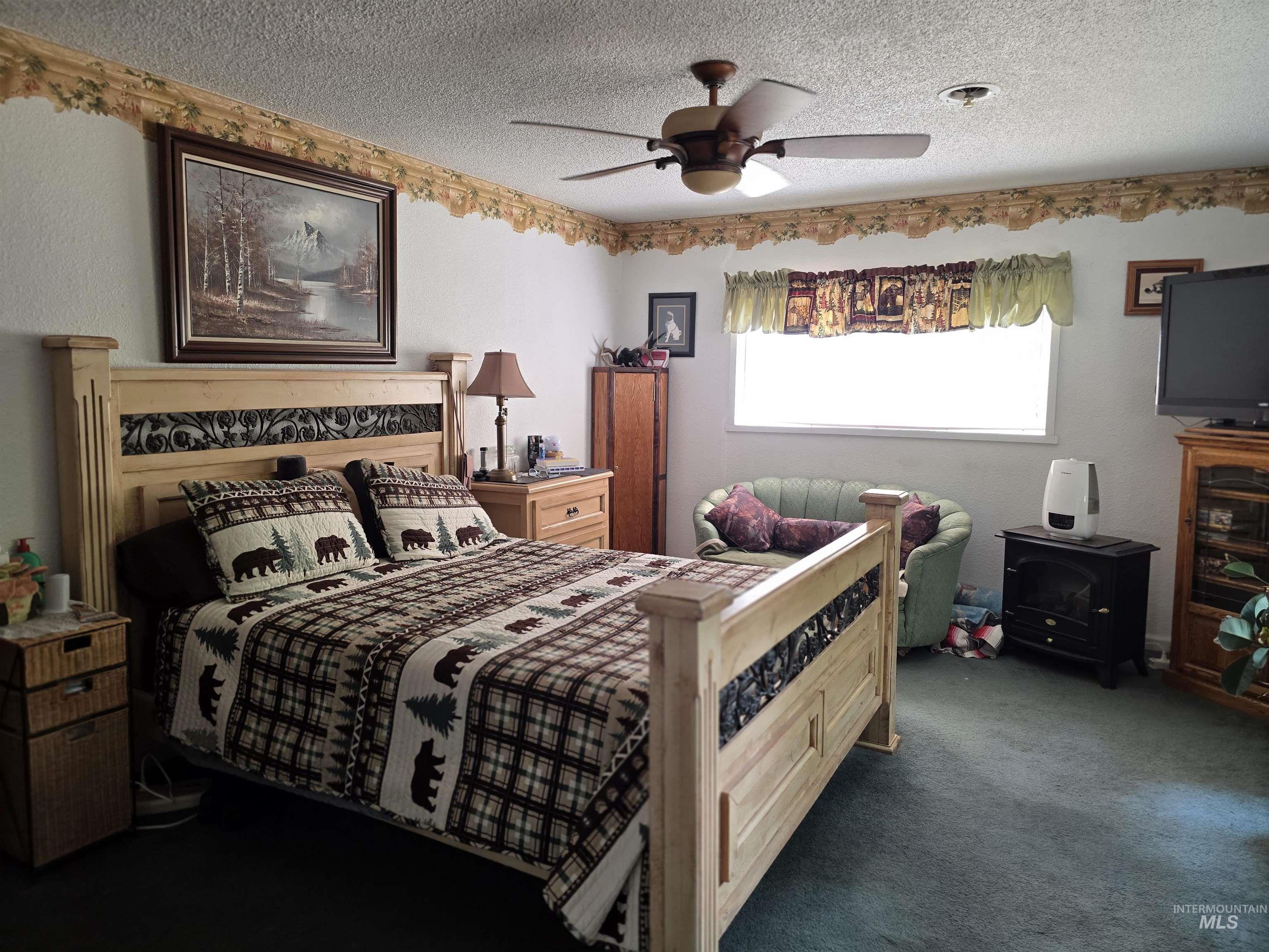 Bedroom featuring dark colored carpet, a textured ceiling, and a ceiling fan