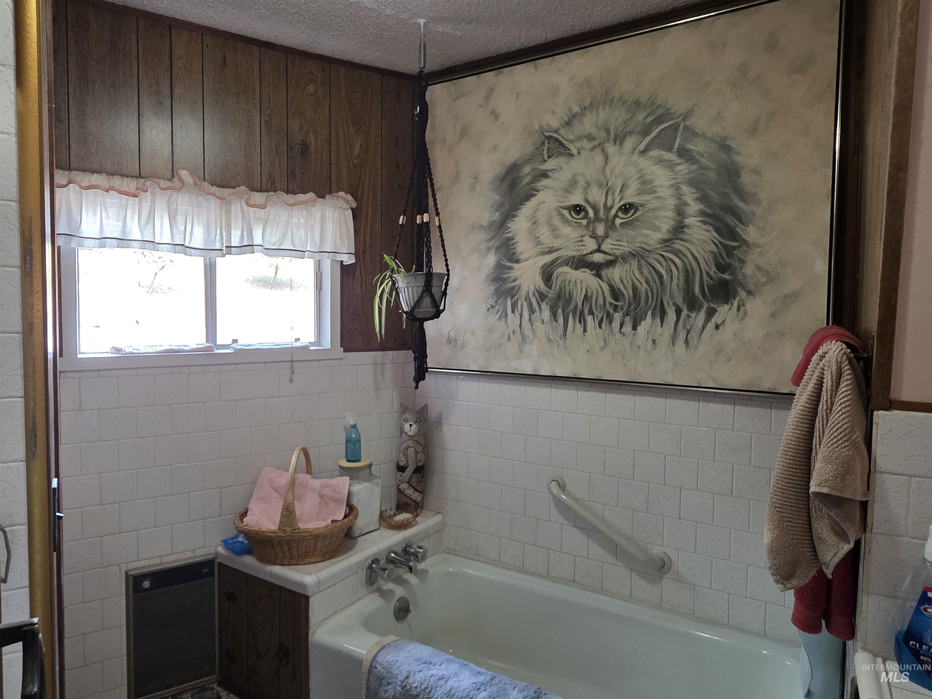 Bathroom featuring a bath, a textured ceiling, and tile walls