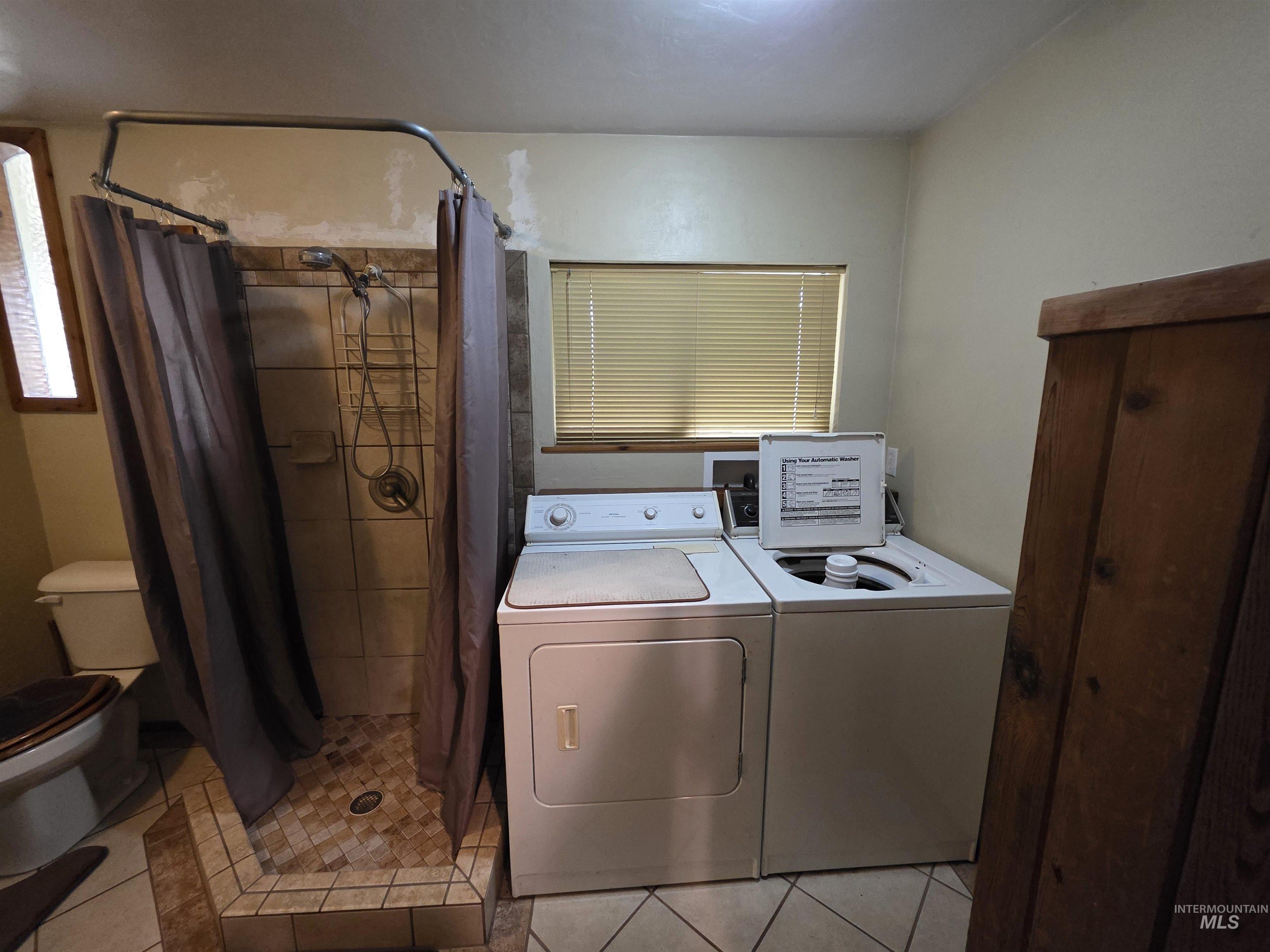 Washroom featuring light tile patterned flooring and washer and clothes dryer