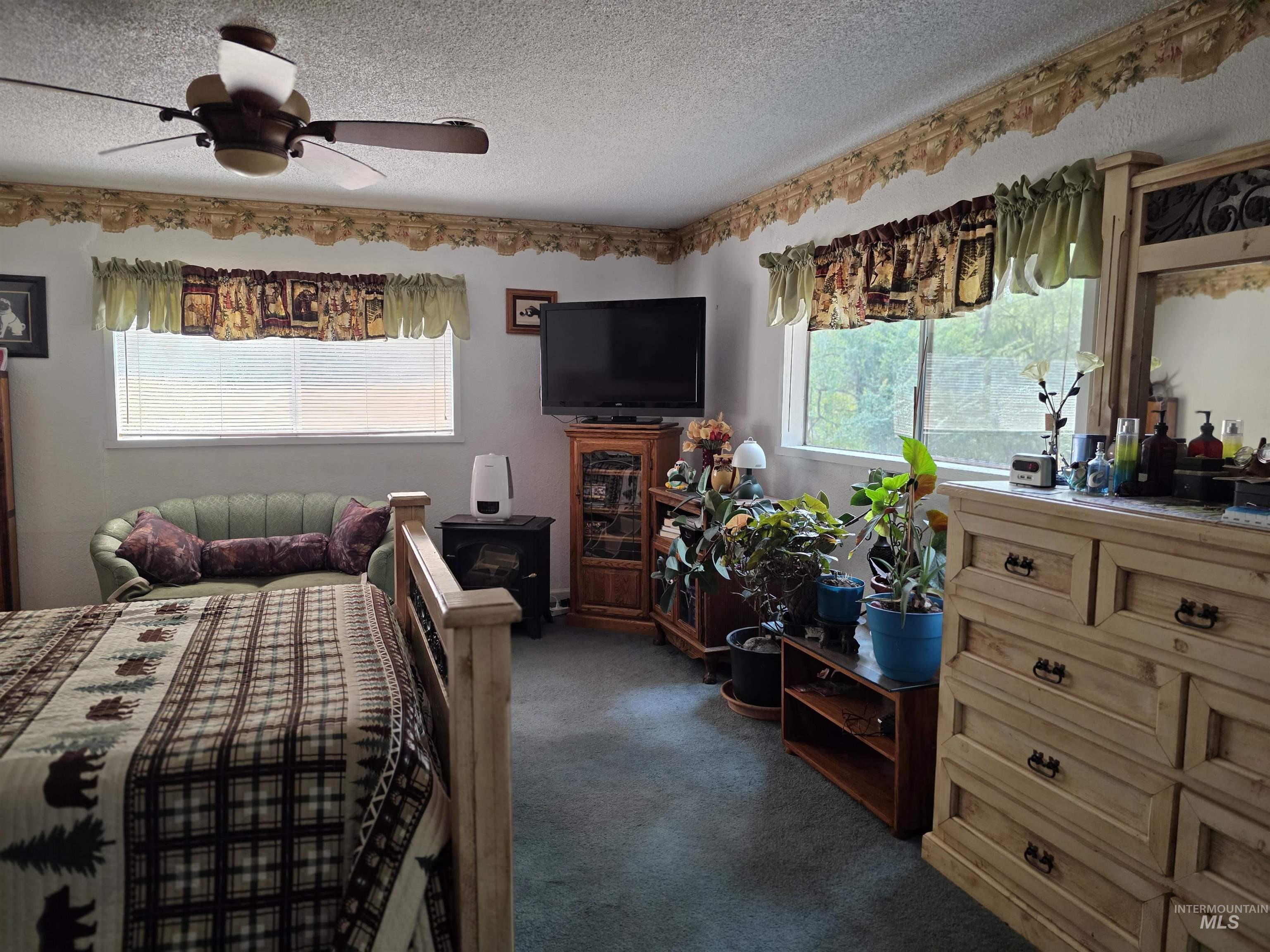 Bedroom with multiple windows, a textured ceiling, dark colored carpet, and ceiling fan
