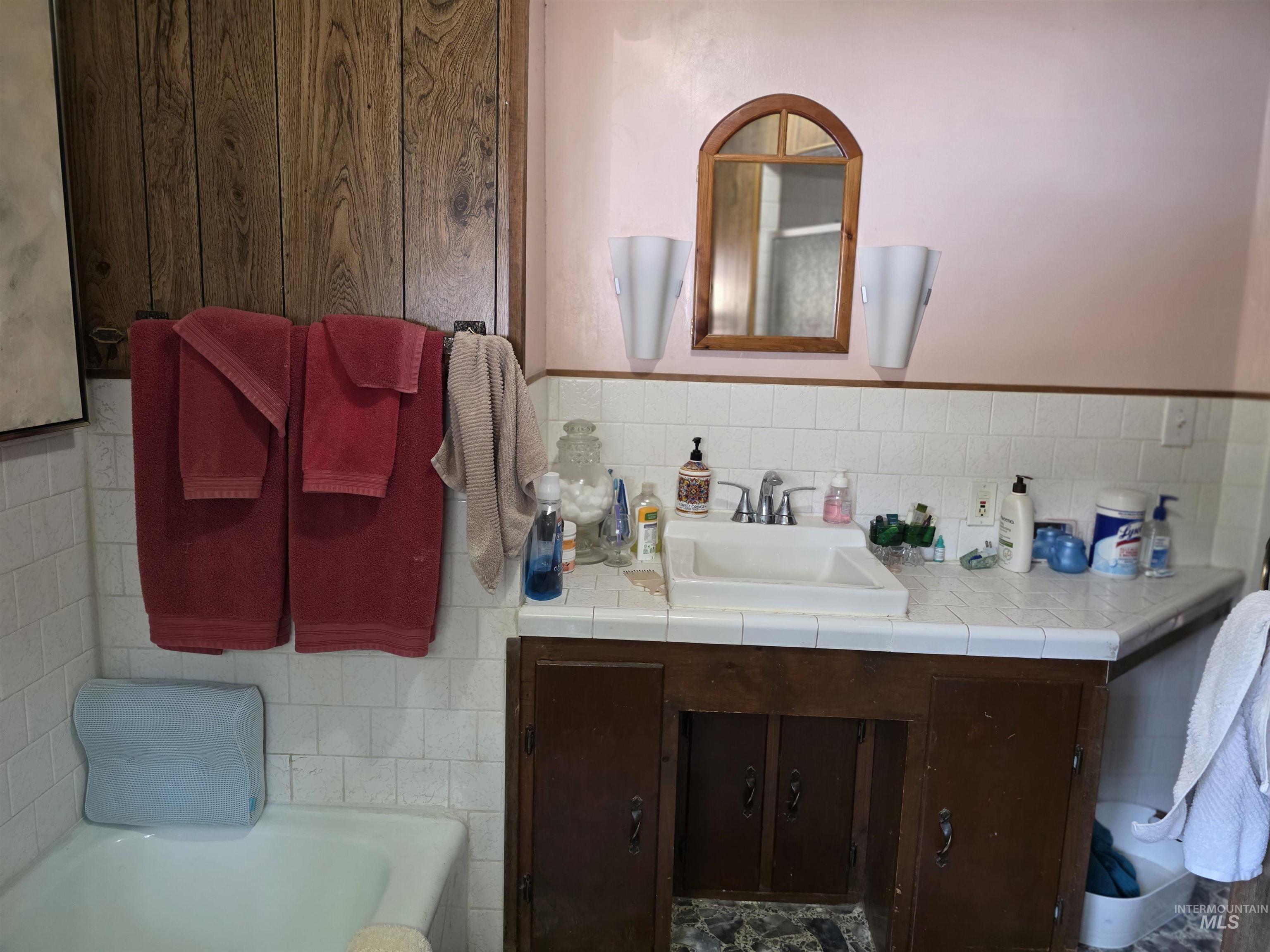 Bathroom with vanity, a garden tub, tile walls, and tasteful backsplash
