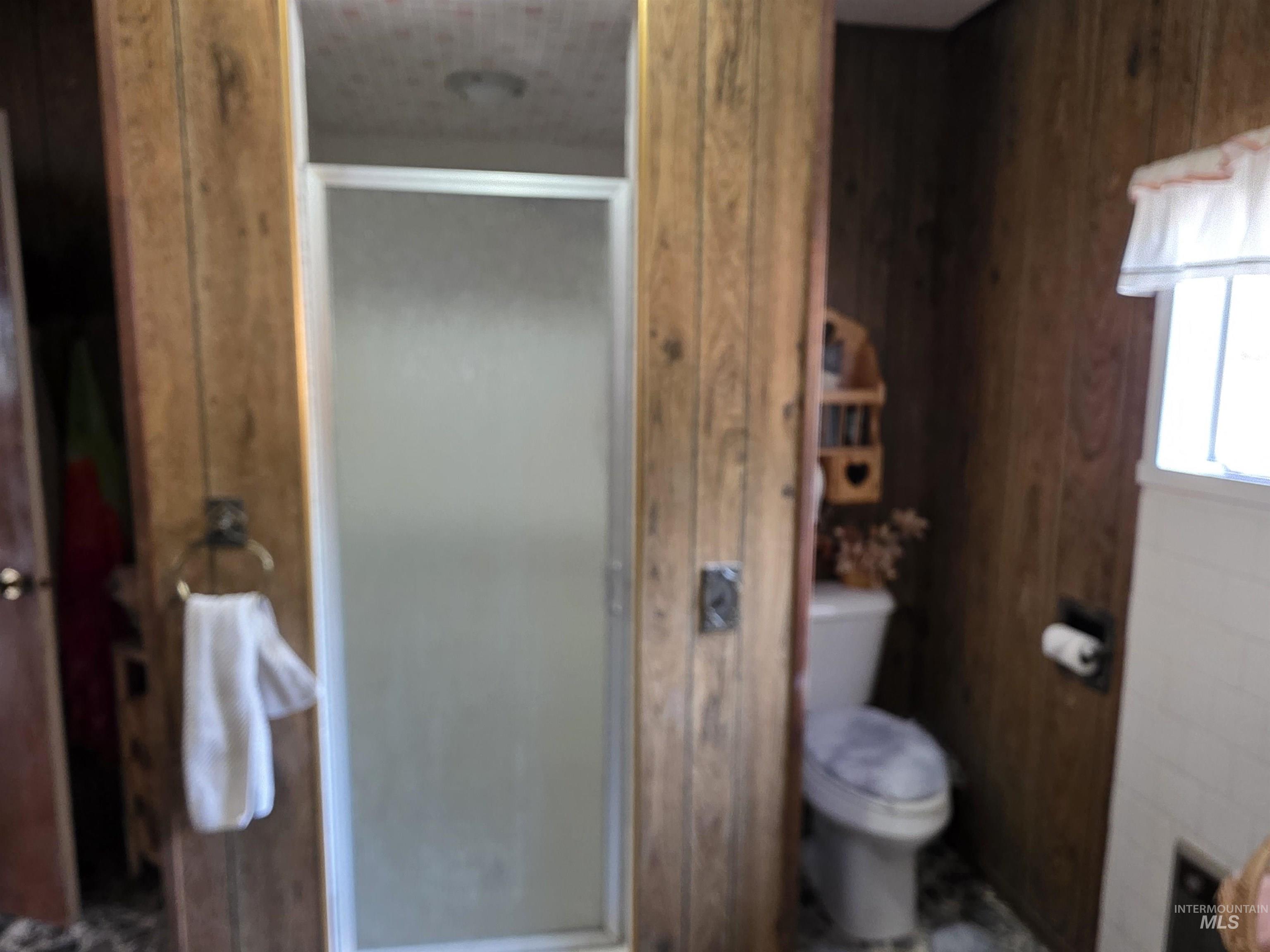 Bathroom with a stall shower and wood walls