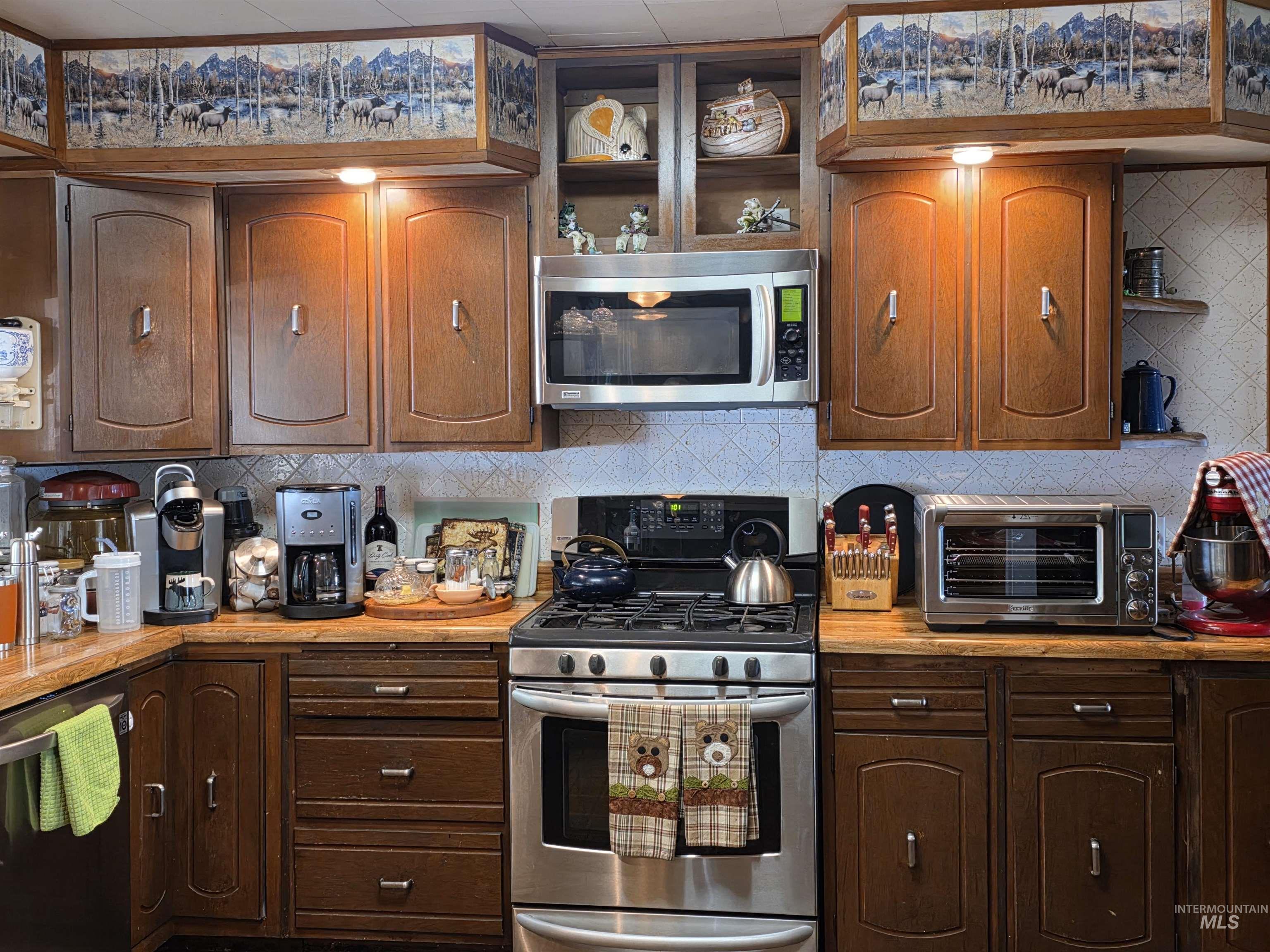 Kitchen with tasteful backsplash, stainless steel appliances, light countertops, open shelves, and brown cabinets