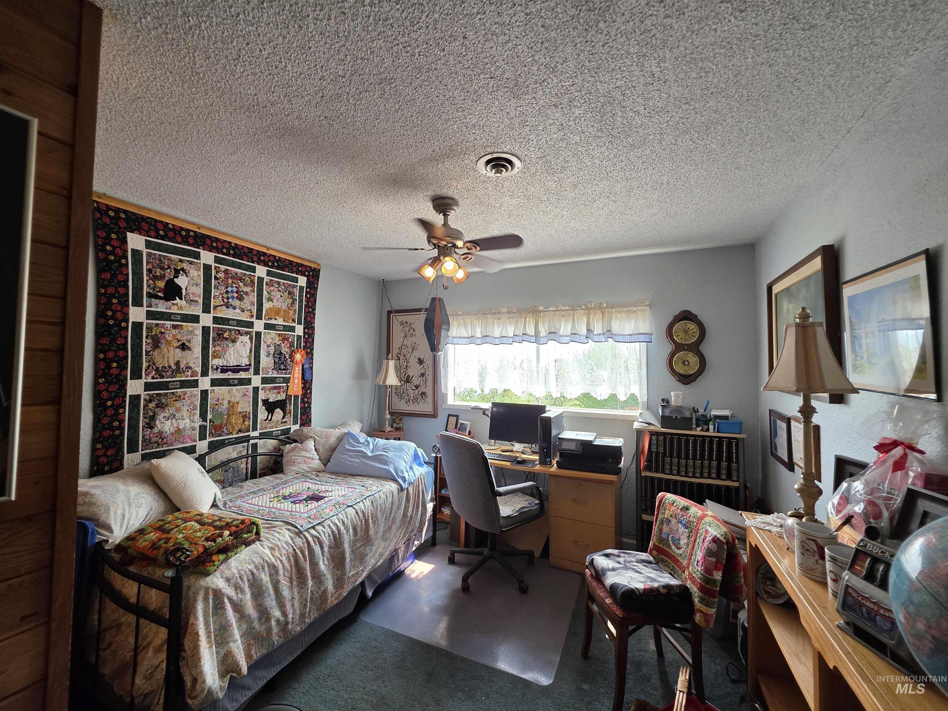 Bedroom featuring a textured ceiling, an office area, and a ceiling fan