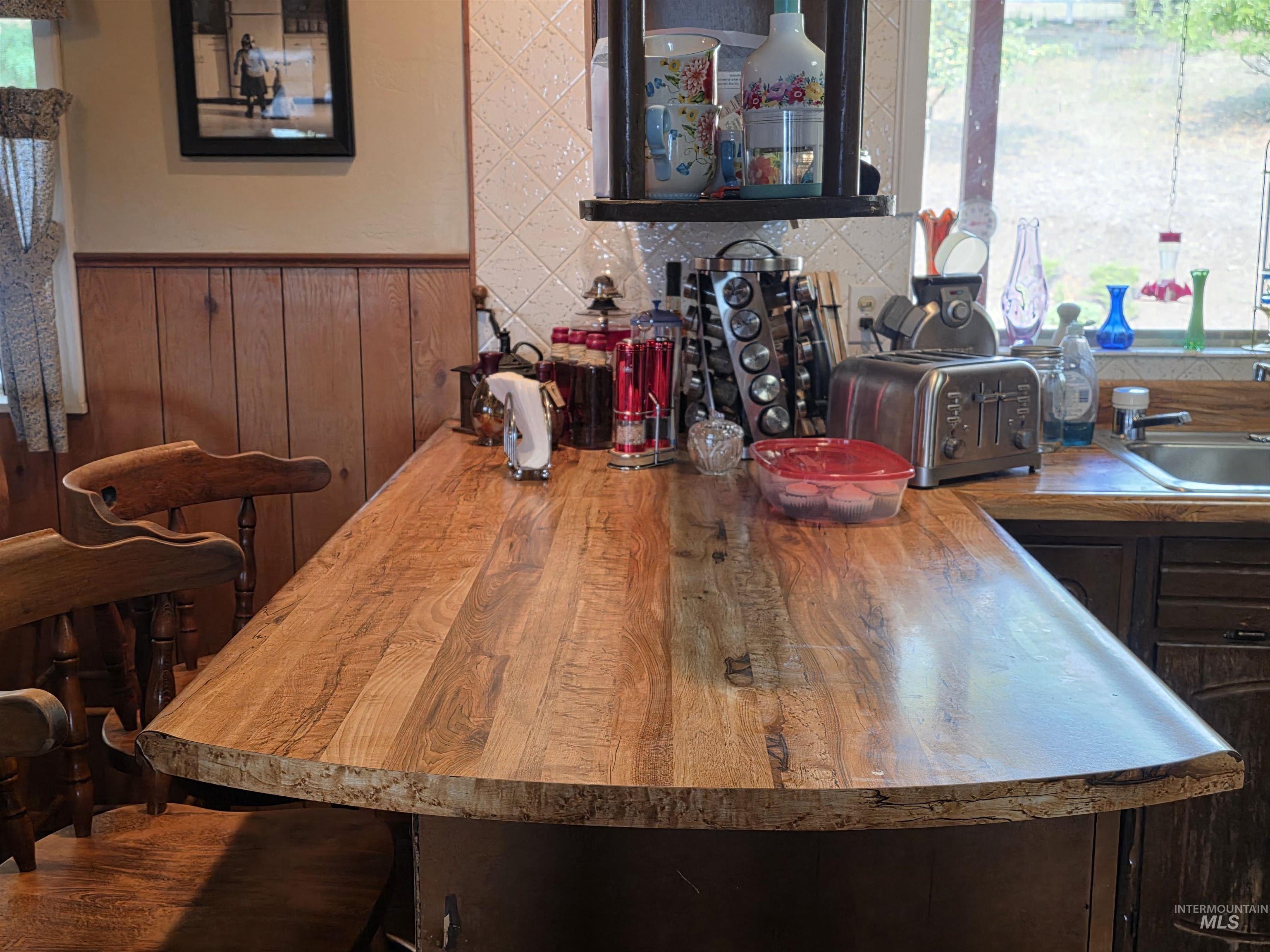 Kitchen with a wainscoted wall, wood counters, wood walls, and a breakfast bar area
