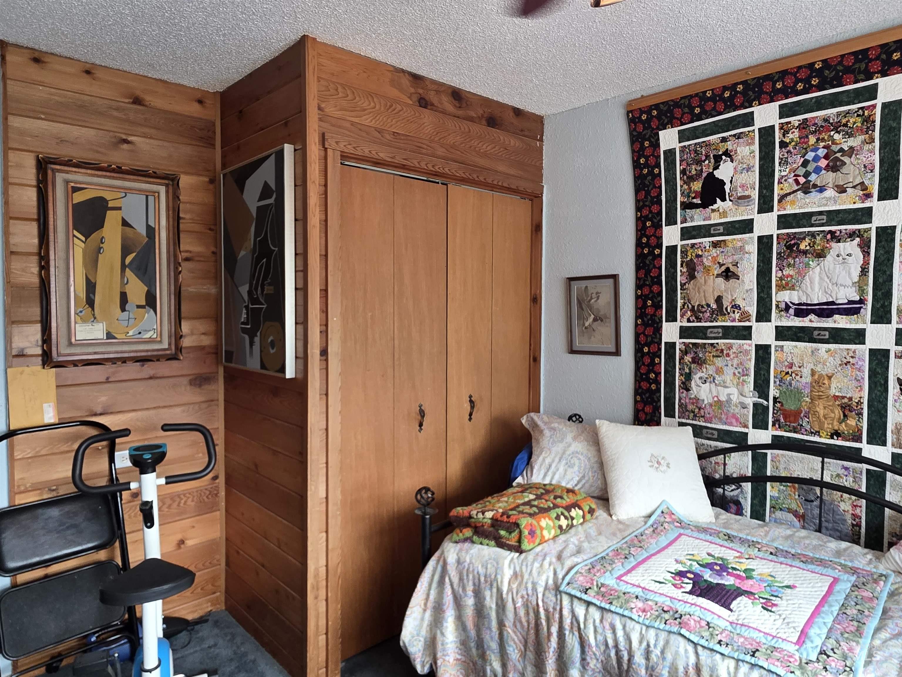 Bedroom with wooden walls, a closet, and a textured ceiling