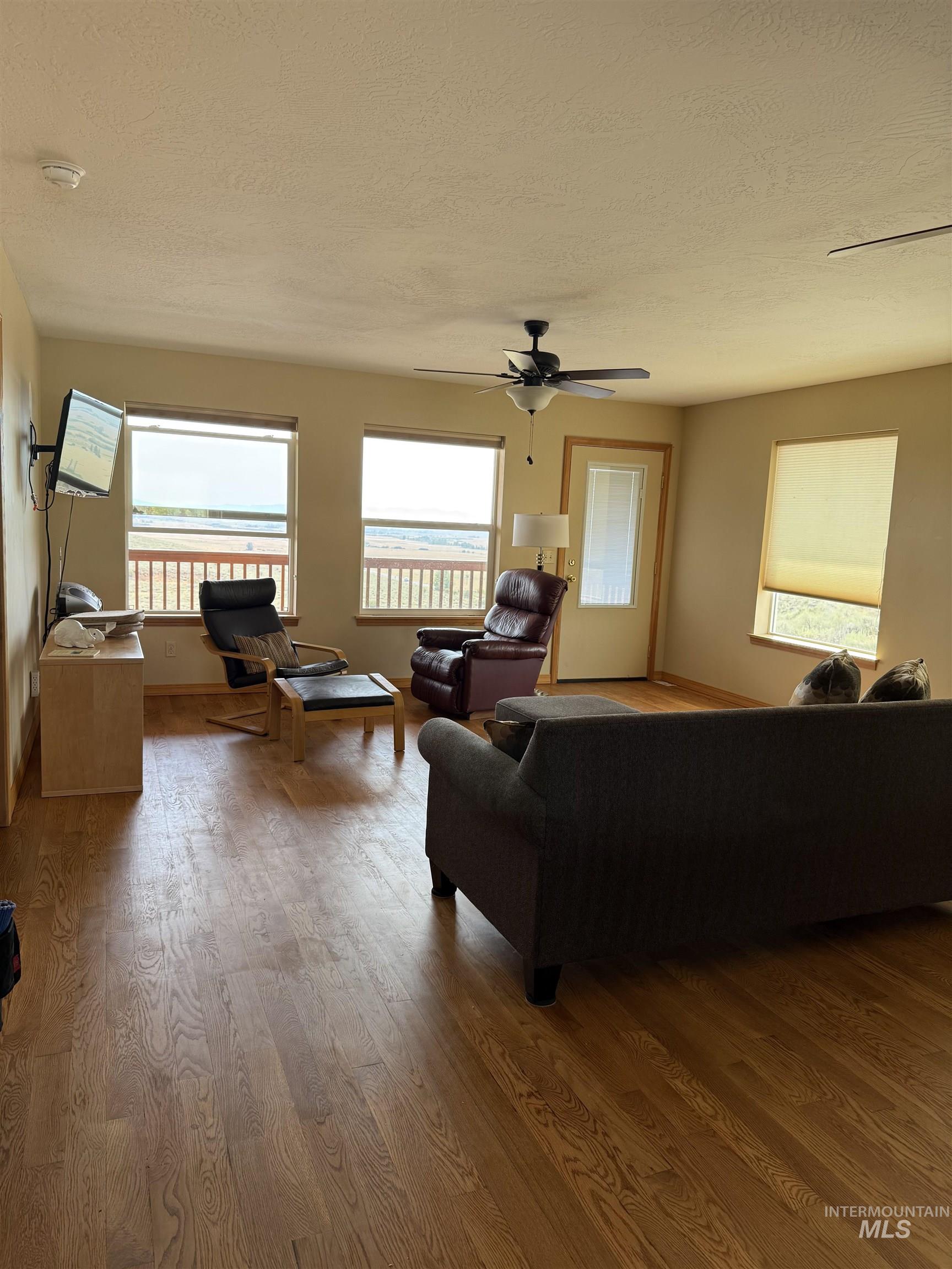 Living area with wood finished floors, a textured ceiling, and ceiling fan