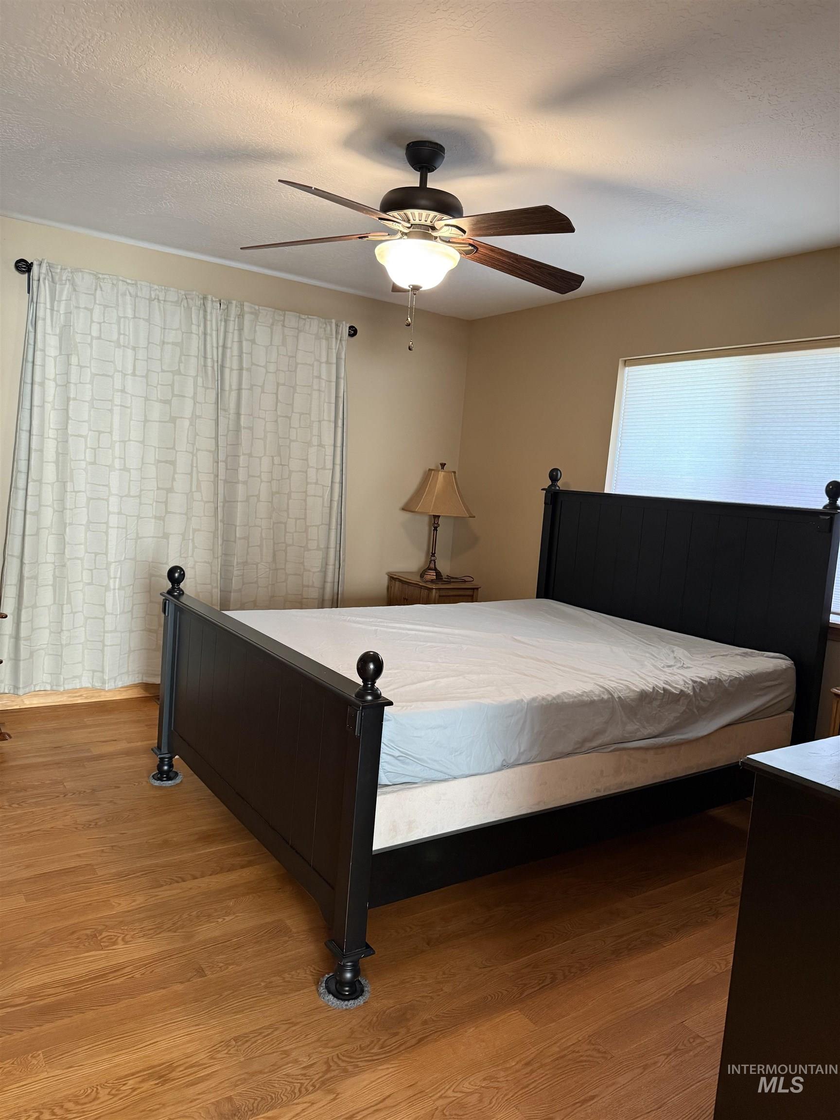 Bedroom with light wood-style flooring, a ceiling fan, and a textured ceiling