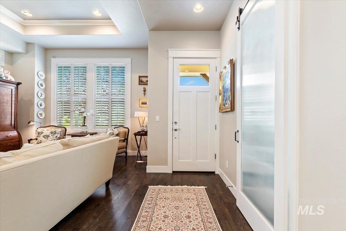 Entrance foyer featuring a barn door, dark wood-style floors, recessed lighting, and a tray ceiling
