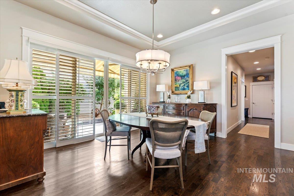Dining space featuring dark wood finished floors, a raised ceiling, a chandelier, and recessed lighting