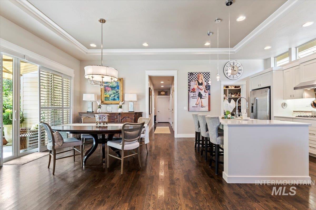 Dining area featuring a tray ceiling, dark wood-style floors, recessed lighting, and a chandelier