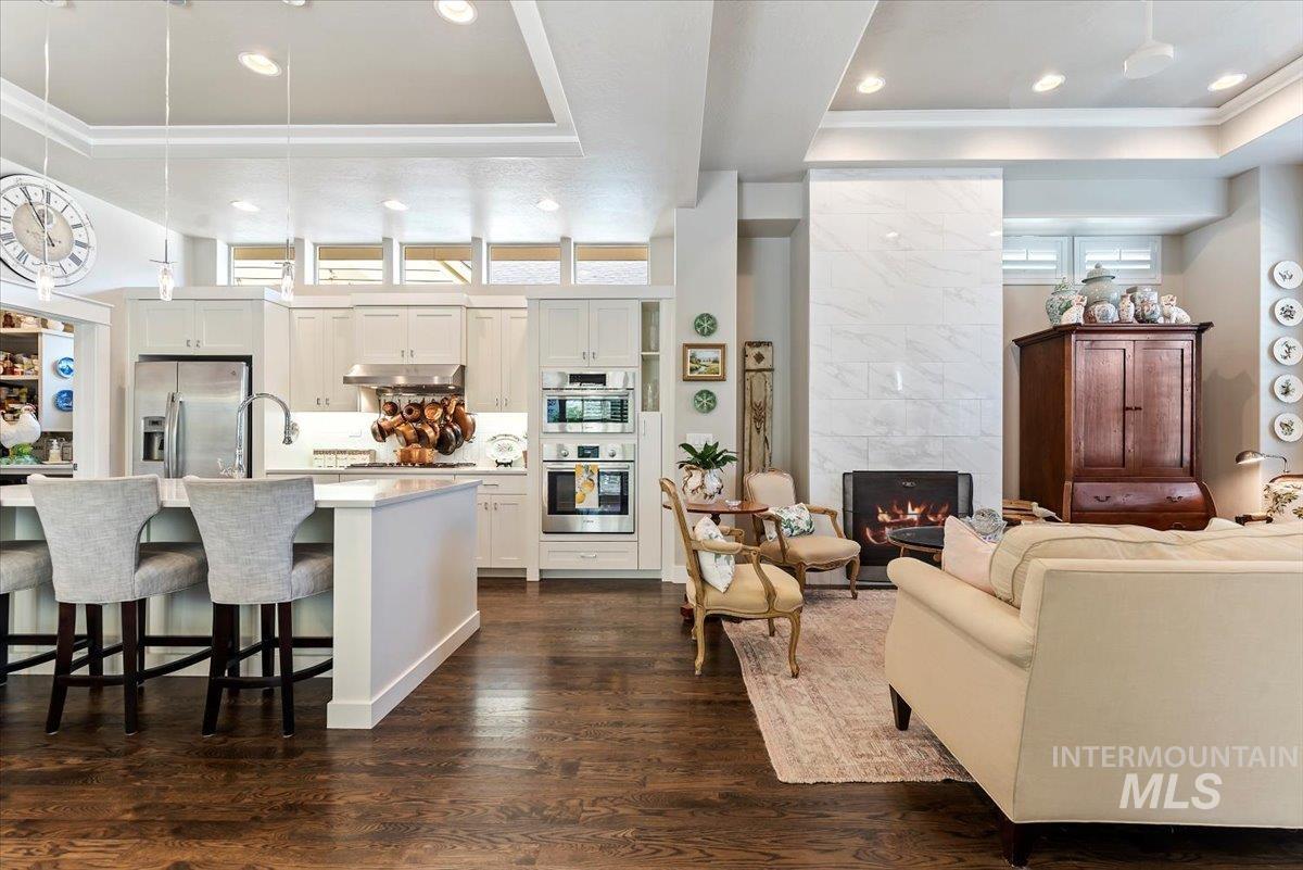 Kitchen featuring a tray ceiling, pendant lighting, a breakfast bar area, a high end fireplace, and appliances with stainless steel finishes