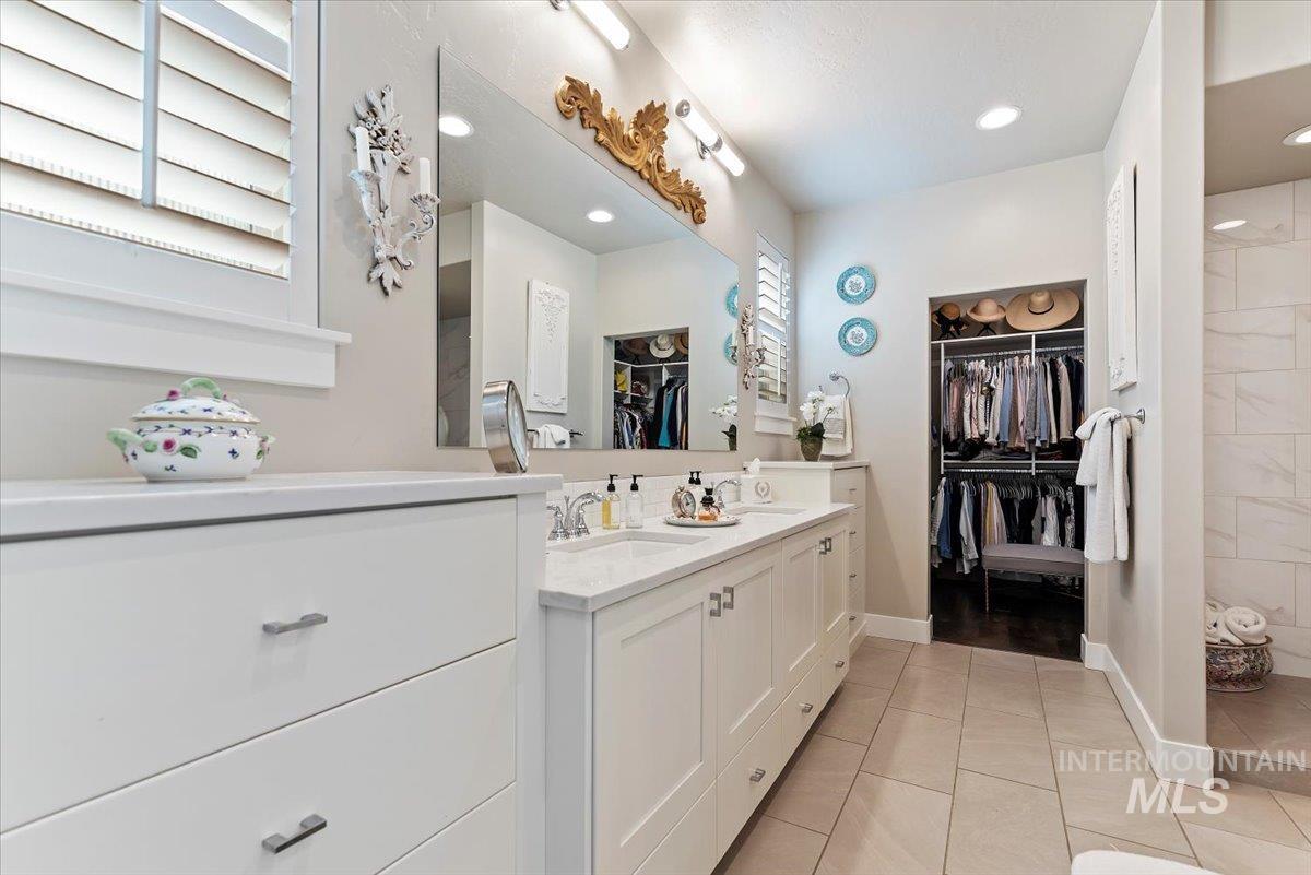 Full bathroom with a walk in closet, double vanity, light tile patterned floors, a tile shower, and recessed lighting