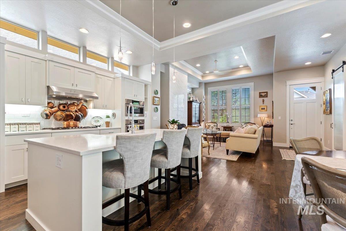 Kitchen with a kitchen breakfast bar, a tray ceiling, hanging light fixtures, dark wood-type flooring, and open floor plan