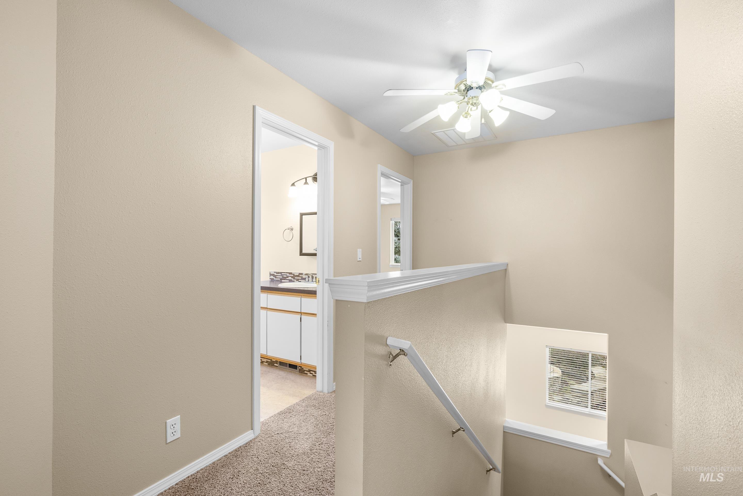 Hall featuring an upstairs landing, carpet flooring, and a textured wall