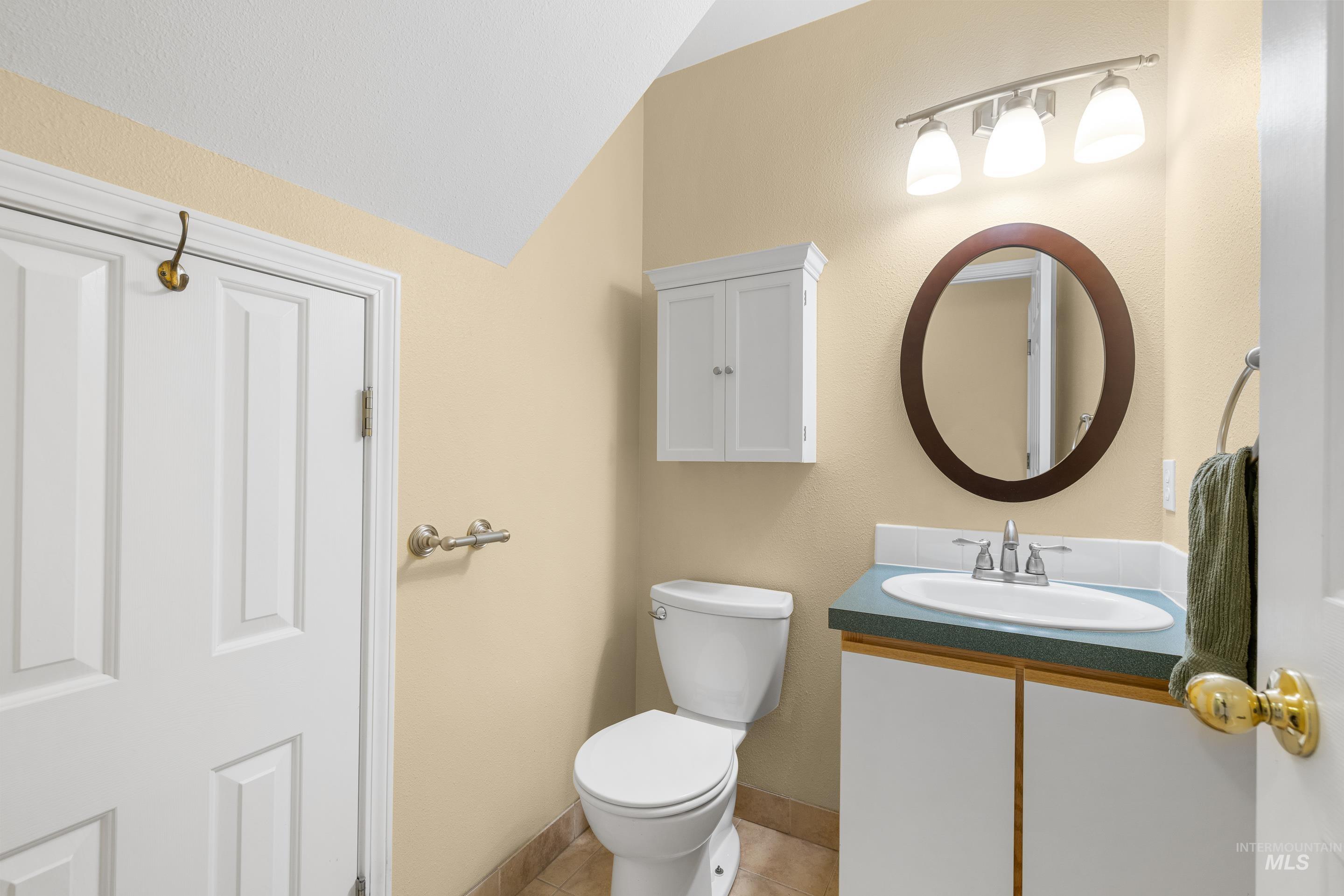 Bathroom featuring vanity, vaulted ceiling, and light tile patterned floors
