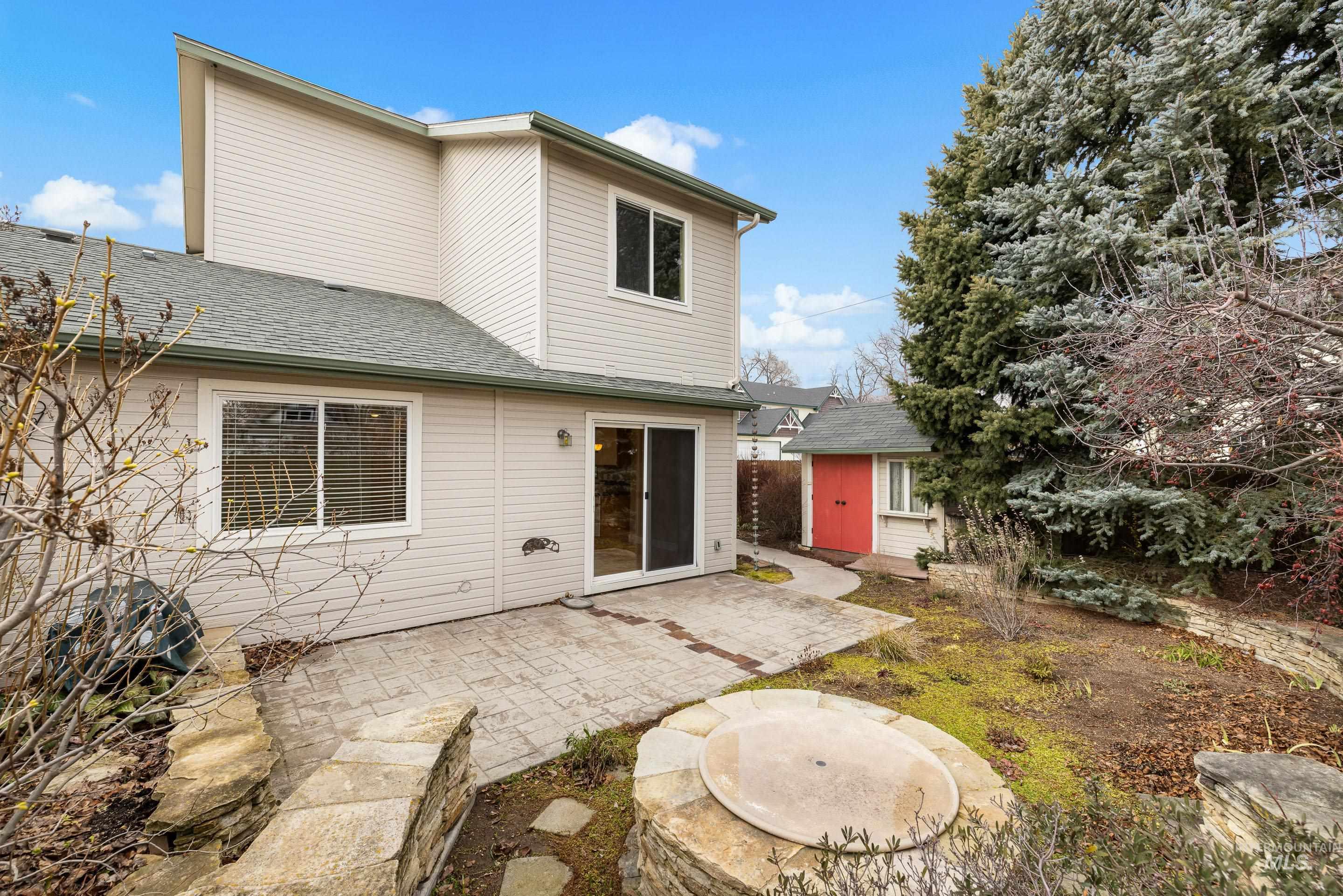 Rear view of house with a patio area, a shingled roof, and a storage unit