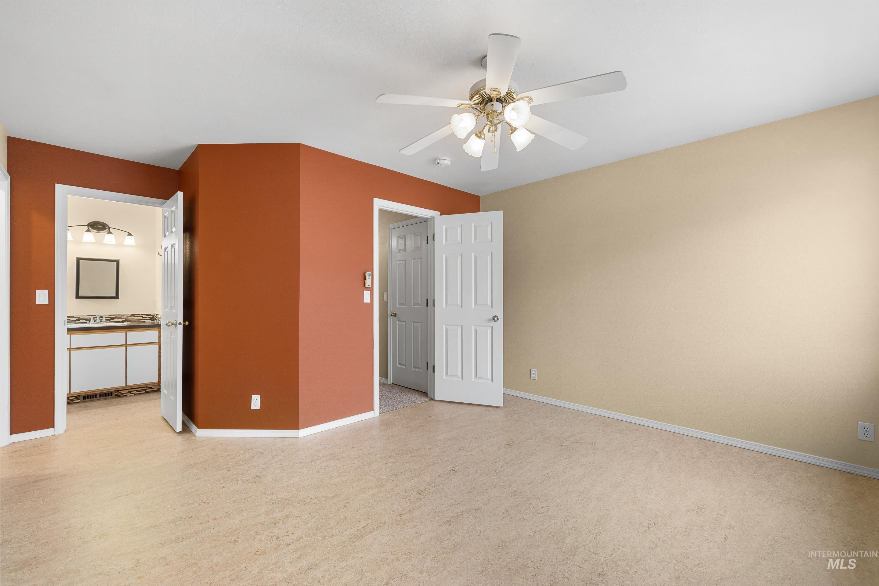 Unfurnished bedroom featuring ceiling fan and ensuite bathroom