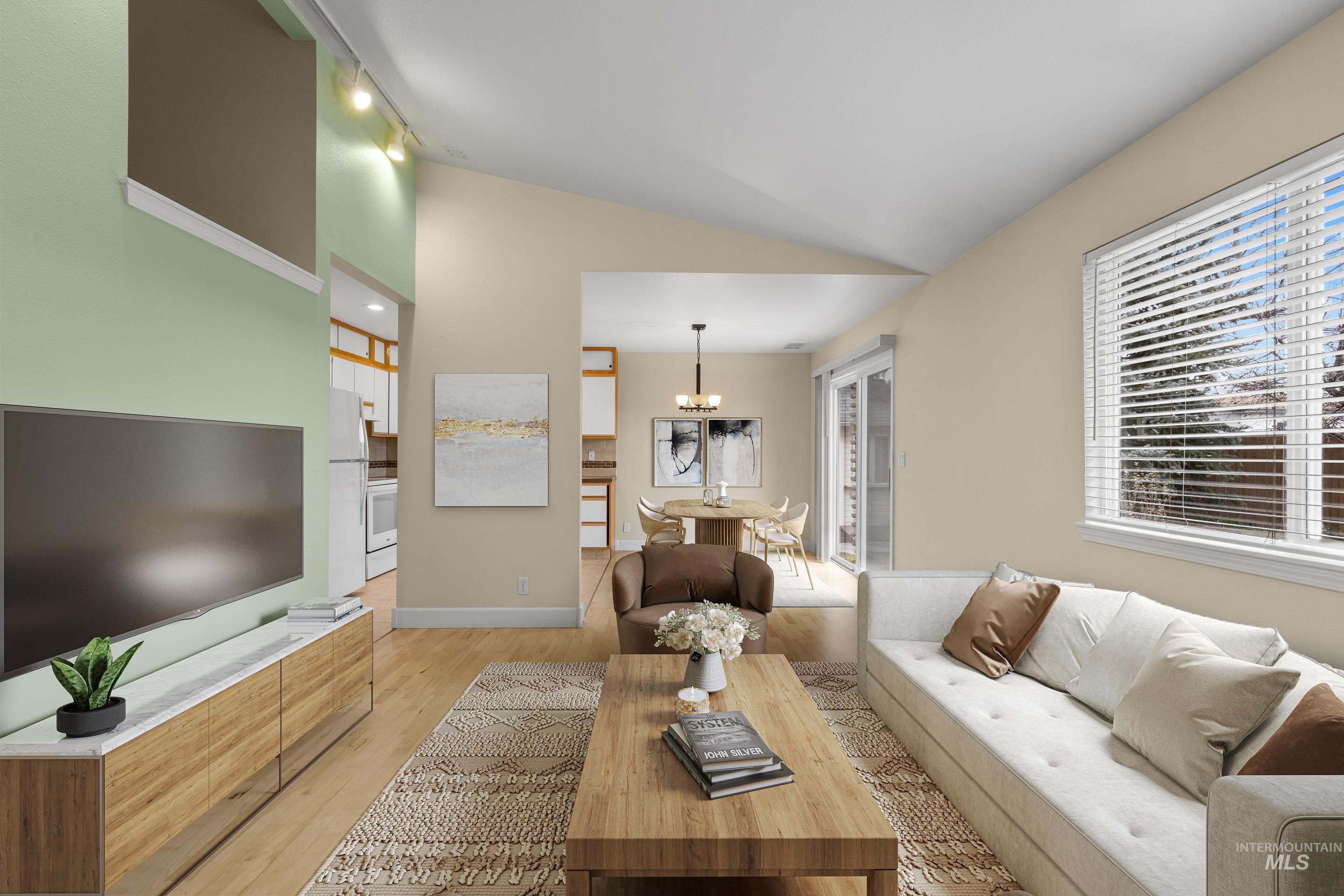 Living room featuring lofted ceiling, light wood-style flooring, and suspended lighting
