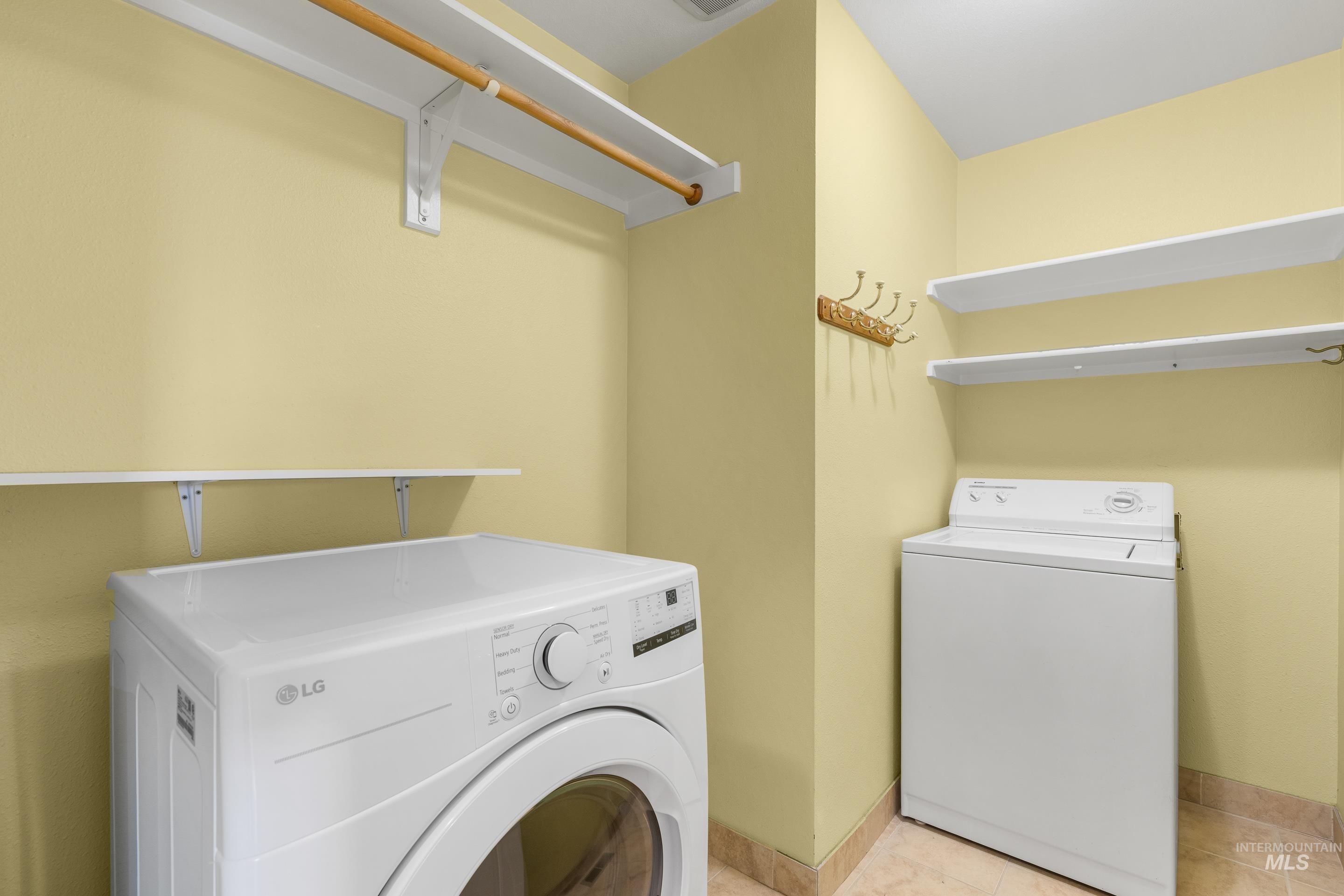 Laundry room with light tile patterned floors and independent washer and dryer