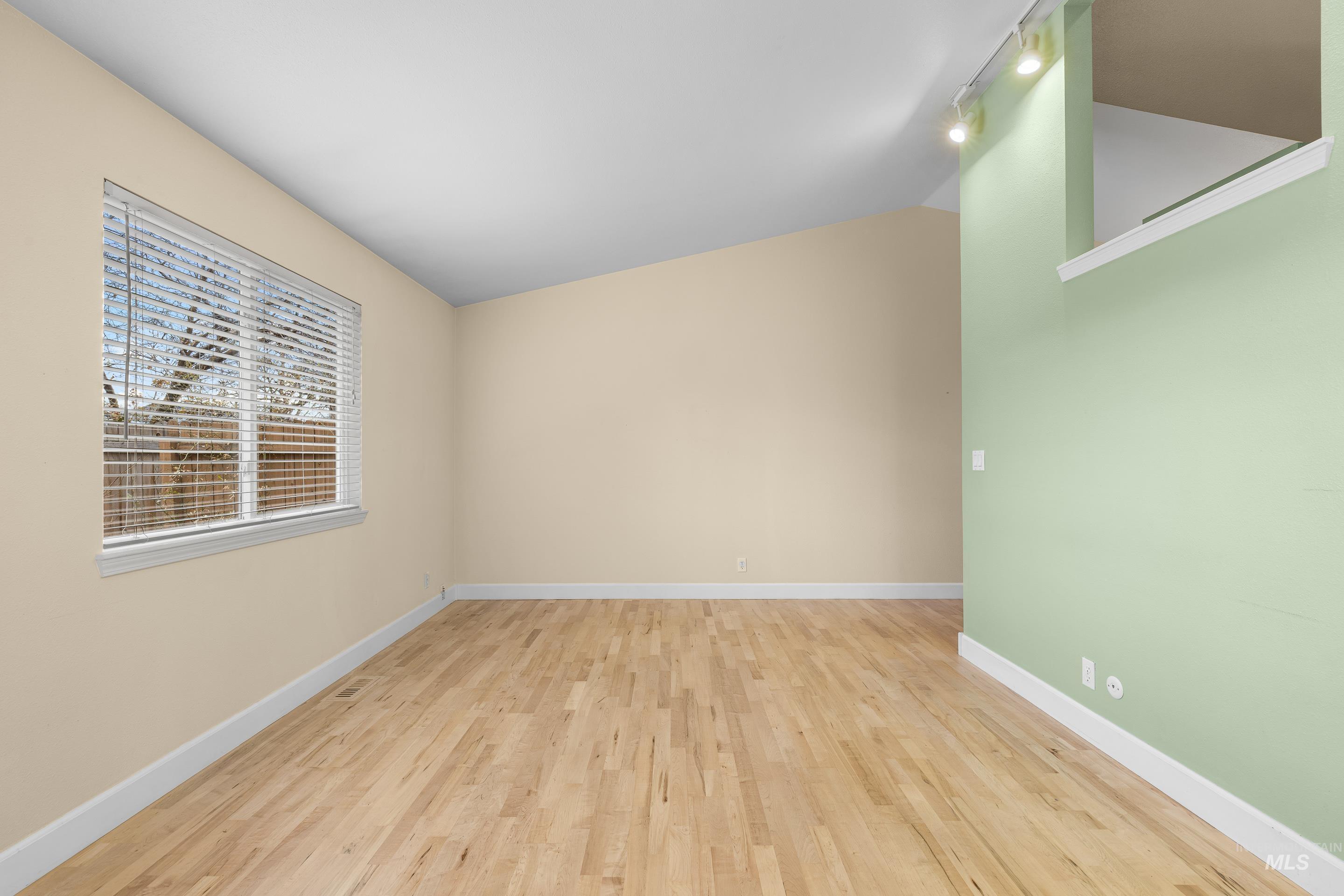 Unfurnished room with light wood finished floors and lofted ceiling