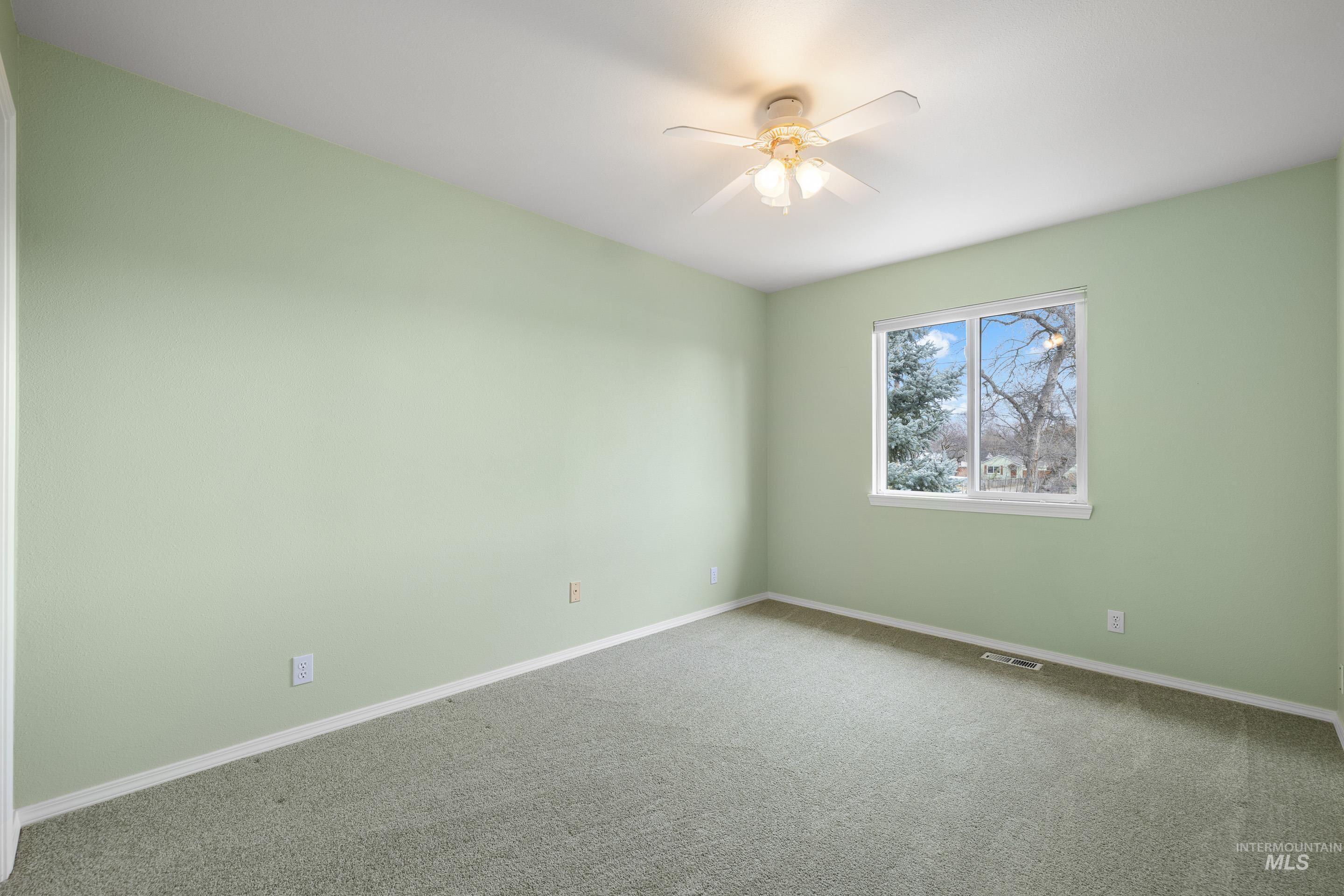 Carpeted spare room featuring baseboards and ceiling fan