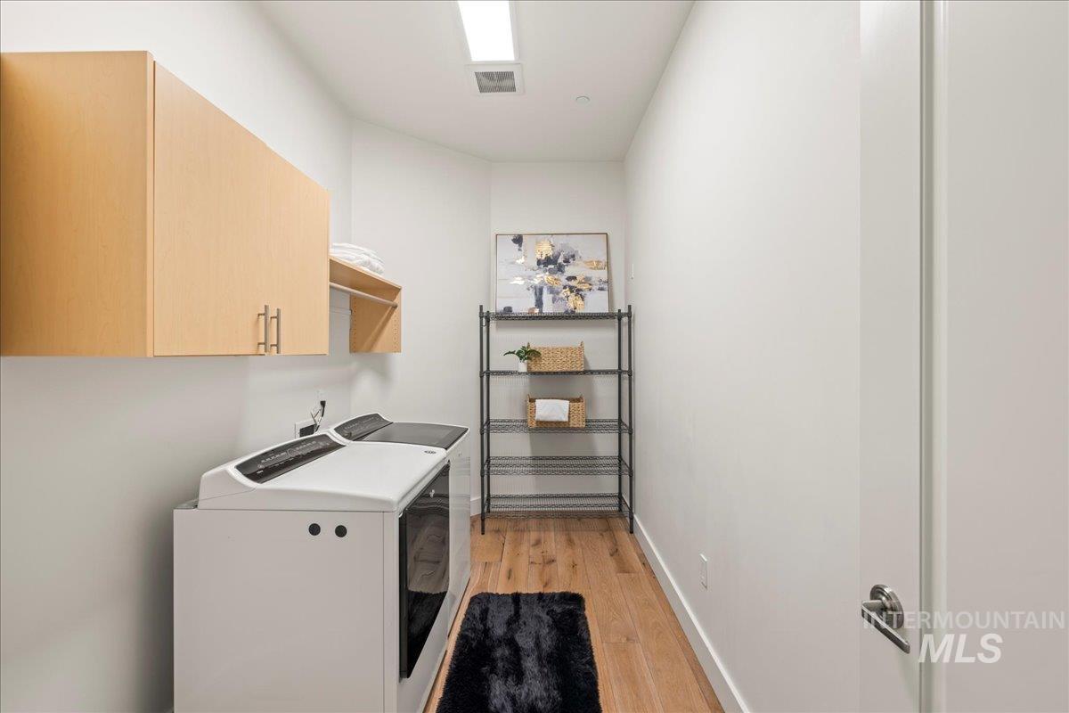 Washroom with cabinet space, light wood-style flooring, and washing machine and dryer