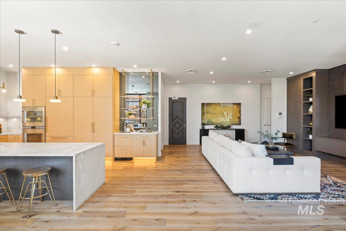 Living area with light wood finished floors and recessed lighting