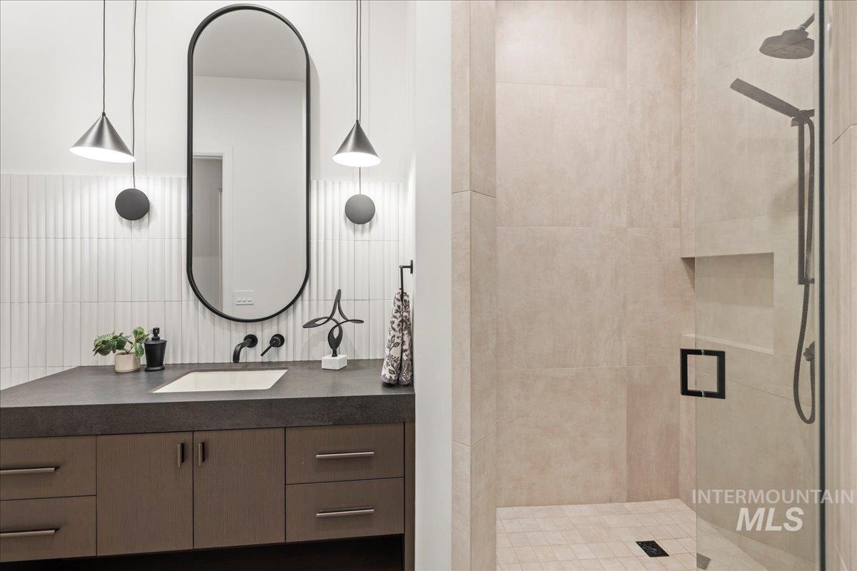 Full bathroom with vanity, a shower stall, and backsplash