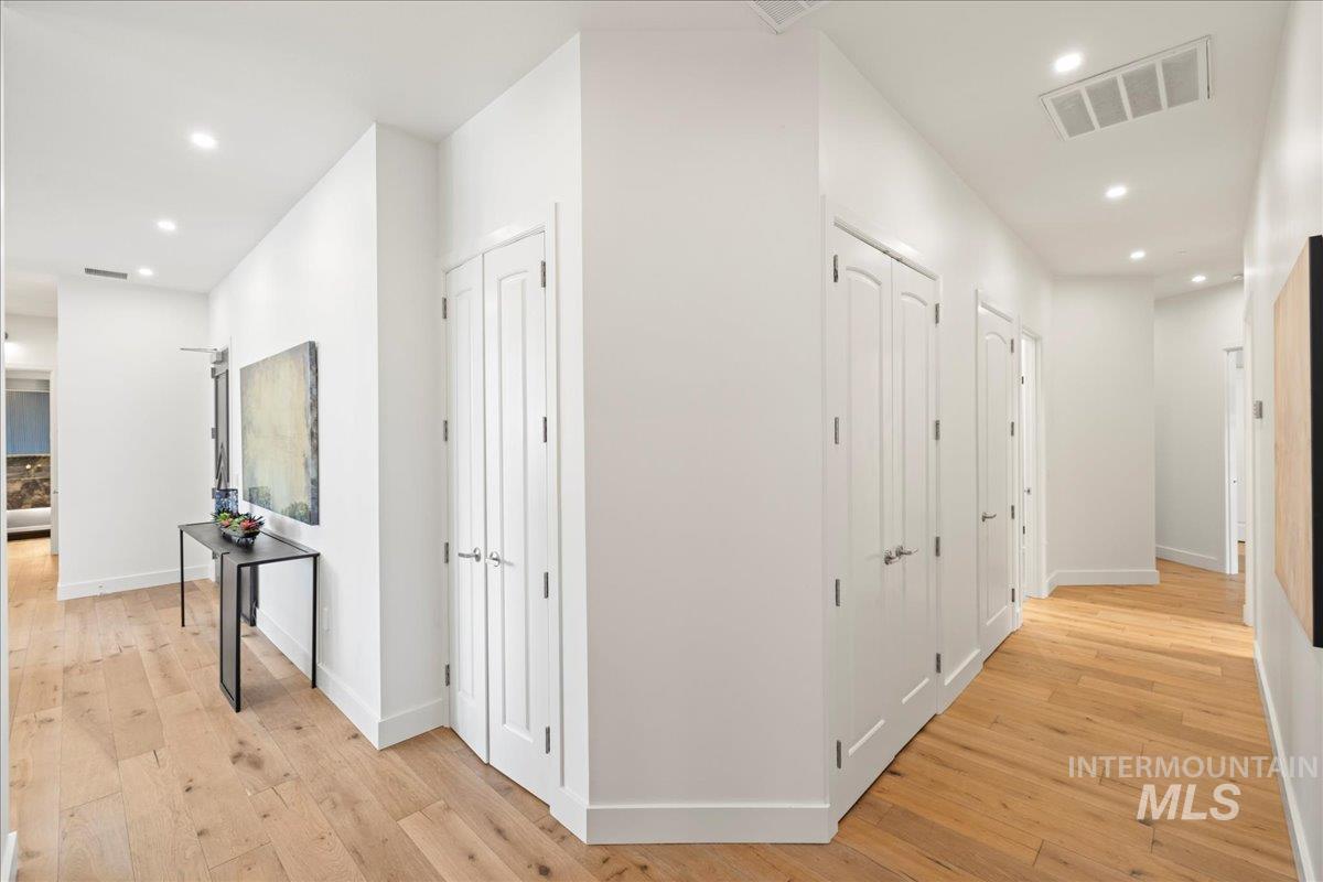 Hallway with light wood-type flooring and recessed lighting