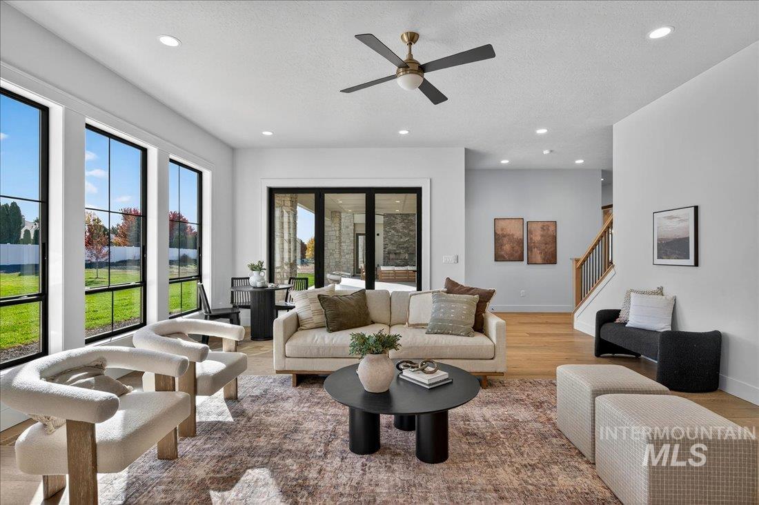 Living room with wood finished floors, recessed lighting, a textured ceiling, ceiling fan, and stairs